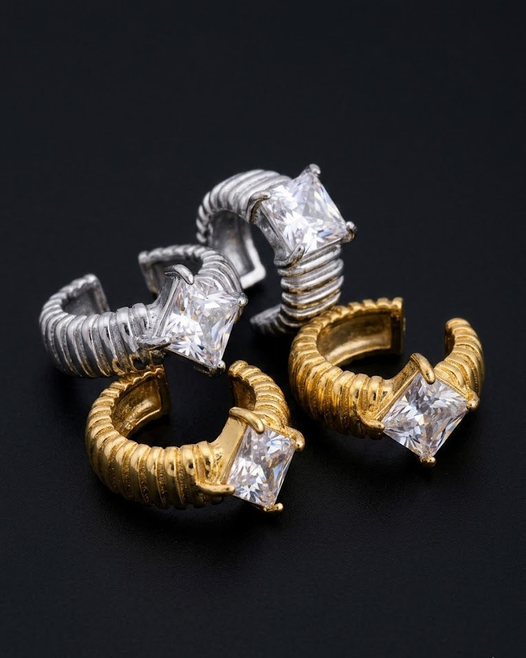 Pair of gold and silver hoop earrings with diamond-like stones on a black background