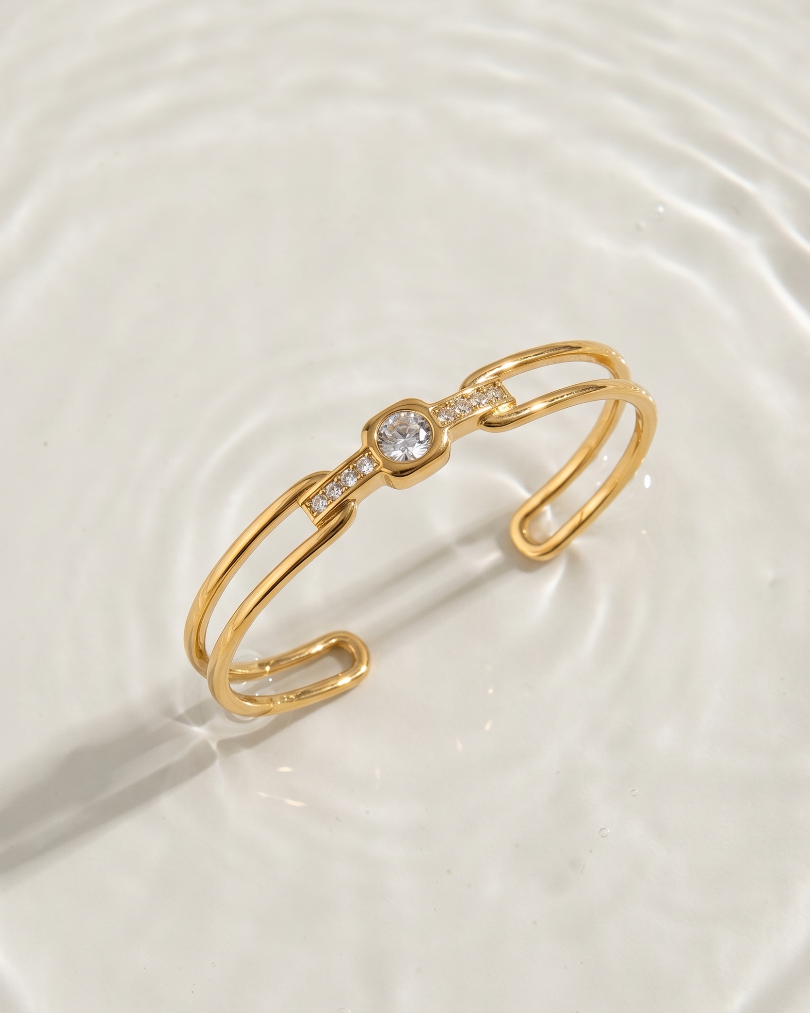 Gold bracelet with a central gemstone on a white fabric background
