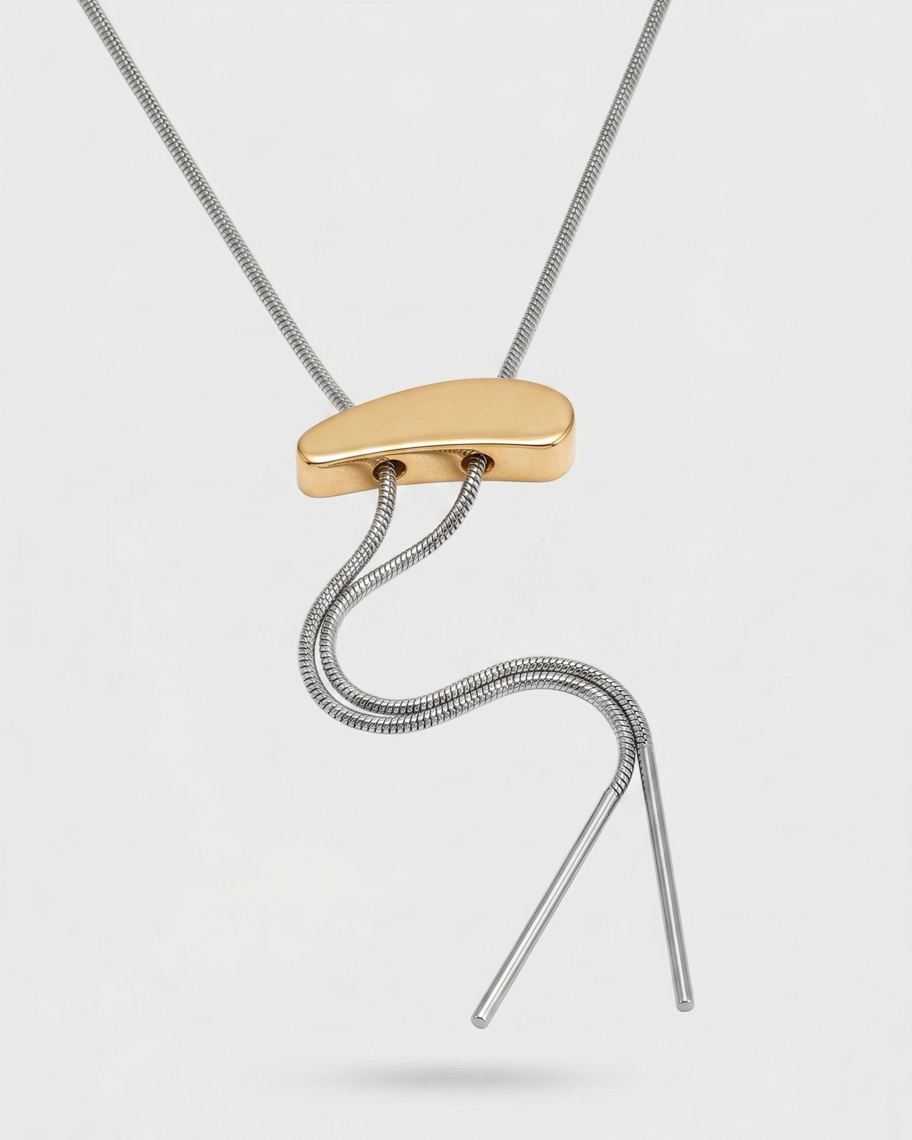 Necklace with a gold and silver pendant on a light gray background