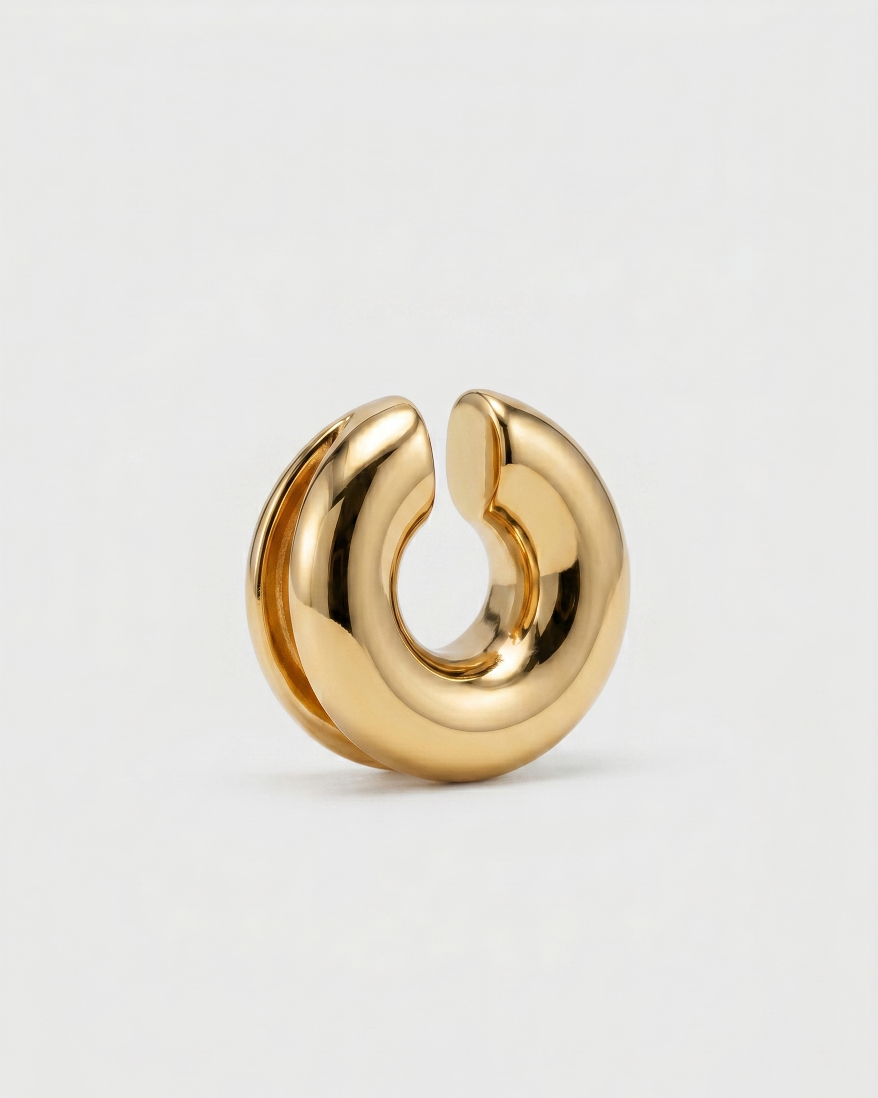 Gold hoop earring on a light gray background
