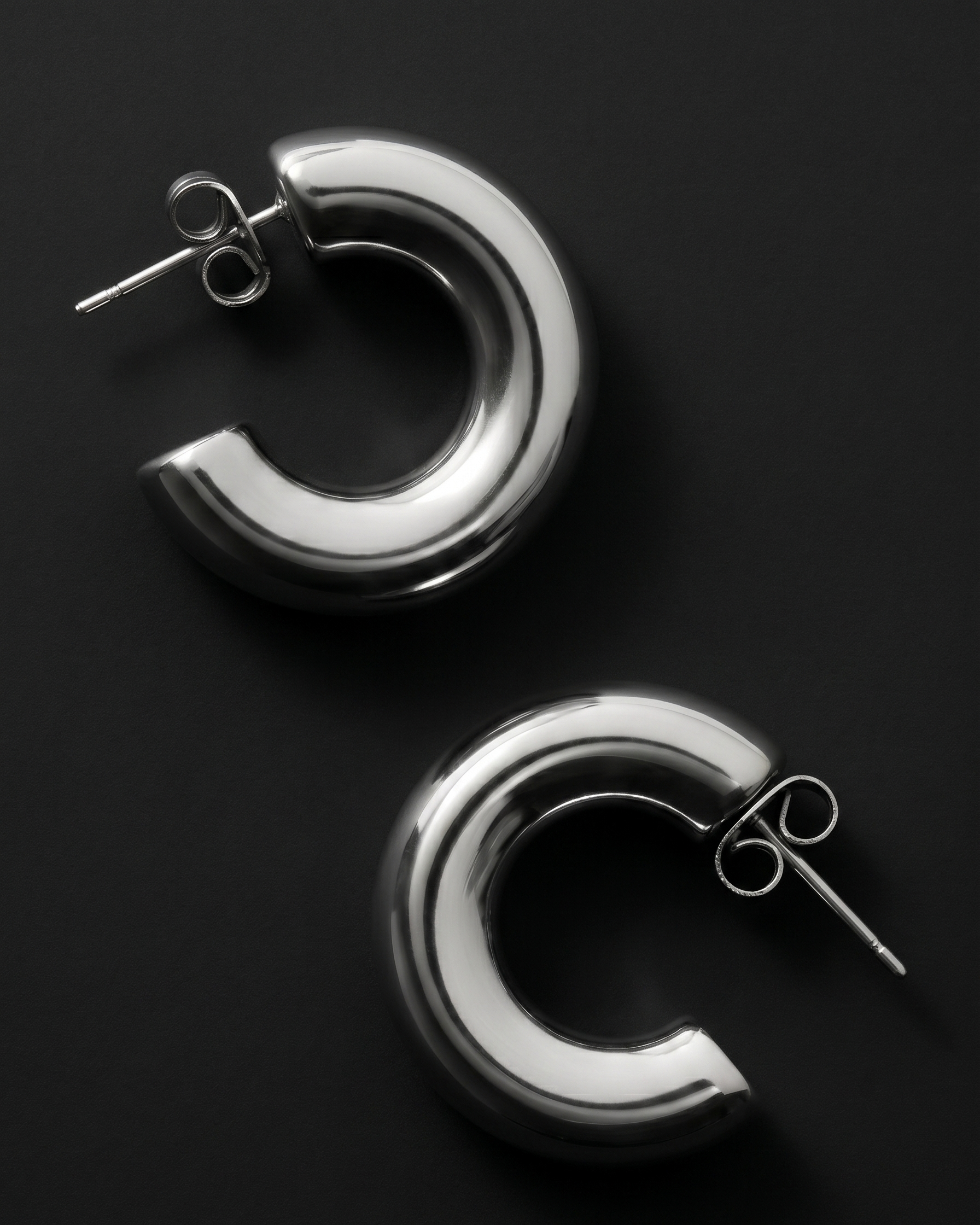 Pair of silver hoop earrings on a black background