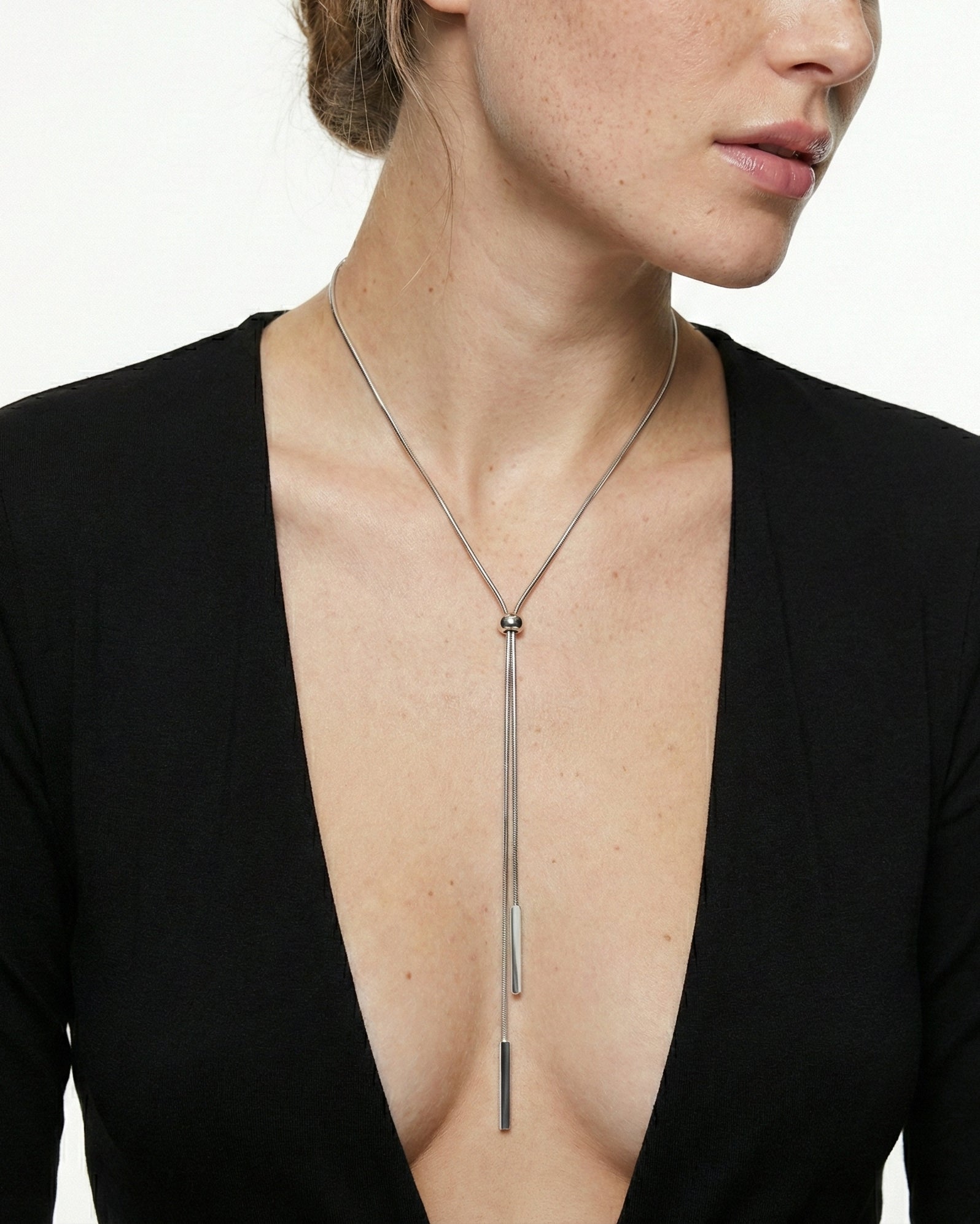 Person wearing a long necklace with a black top