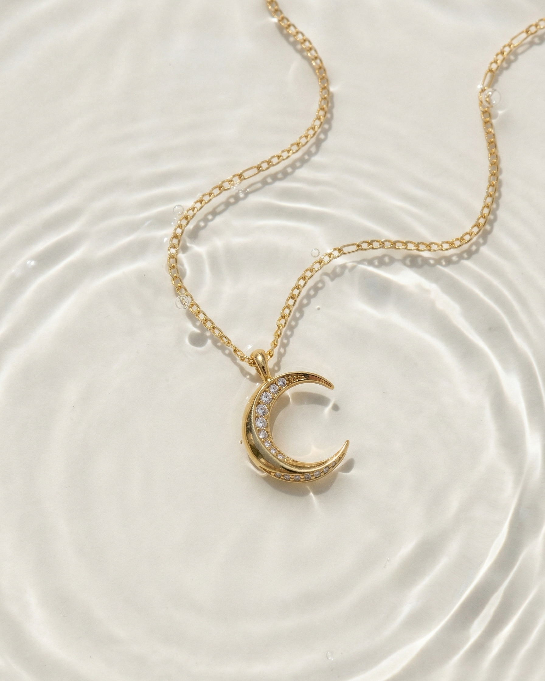 Gold necklace with a crescent moon pendant on a white background