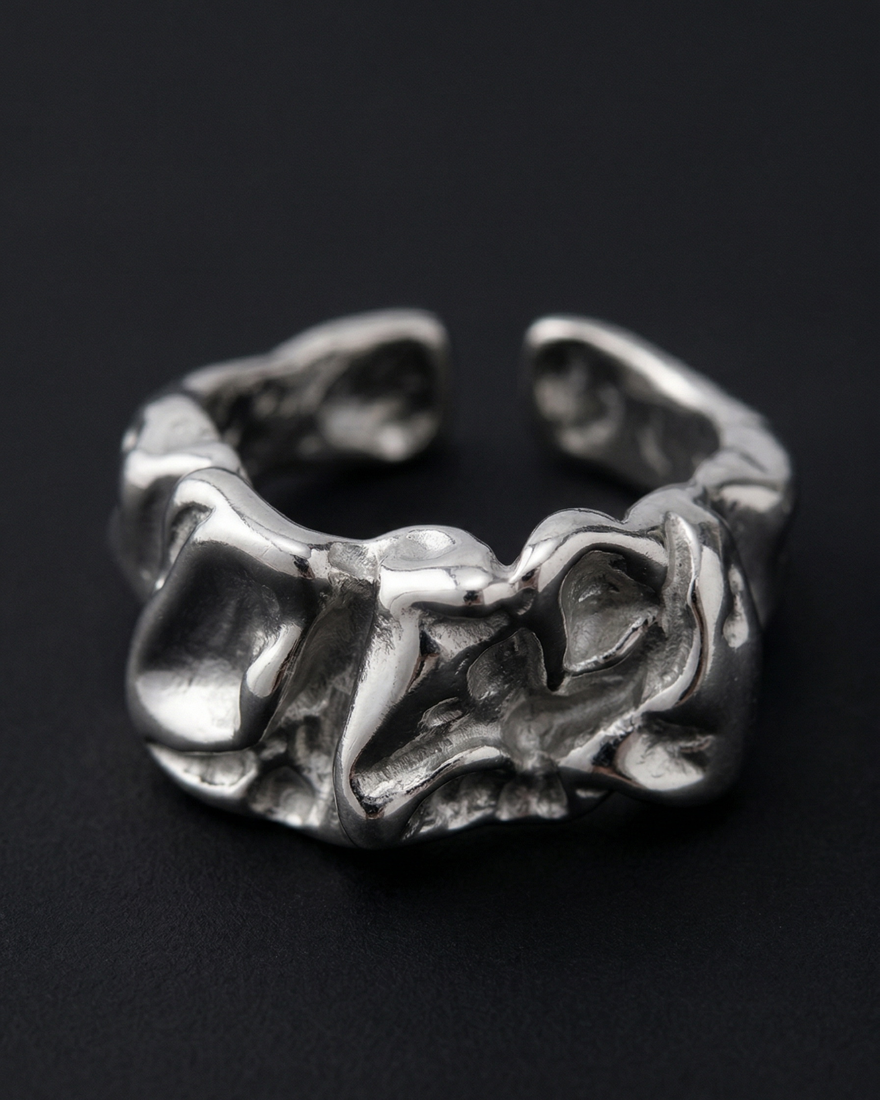 Silver ring with wavy design on a black background