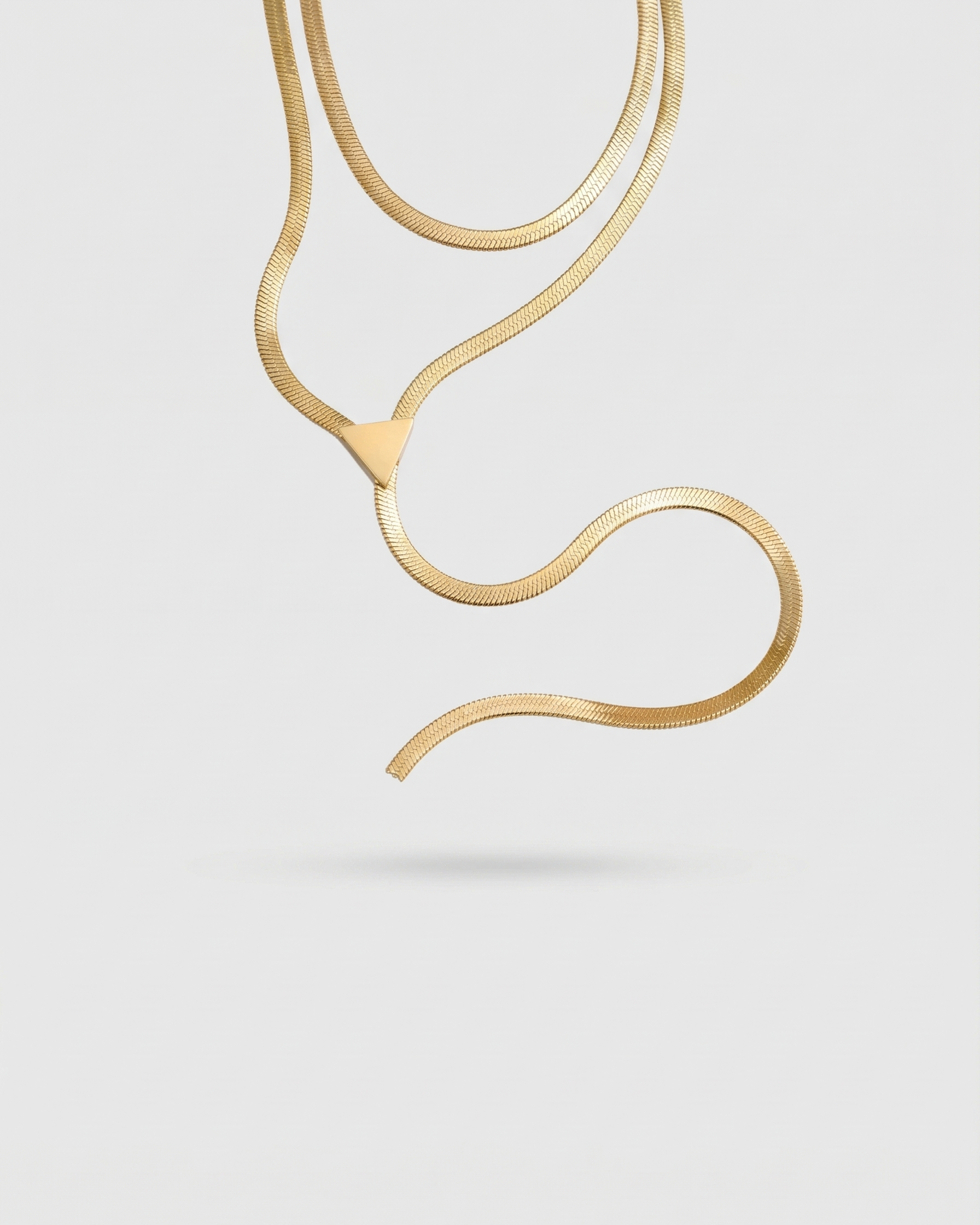 Gold necklace on a light gray background
