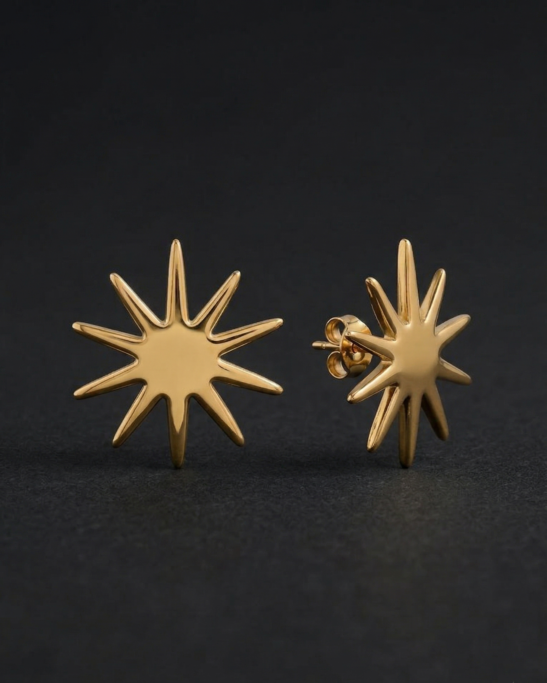 Gold star-shaped earrings on a black background