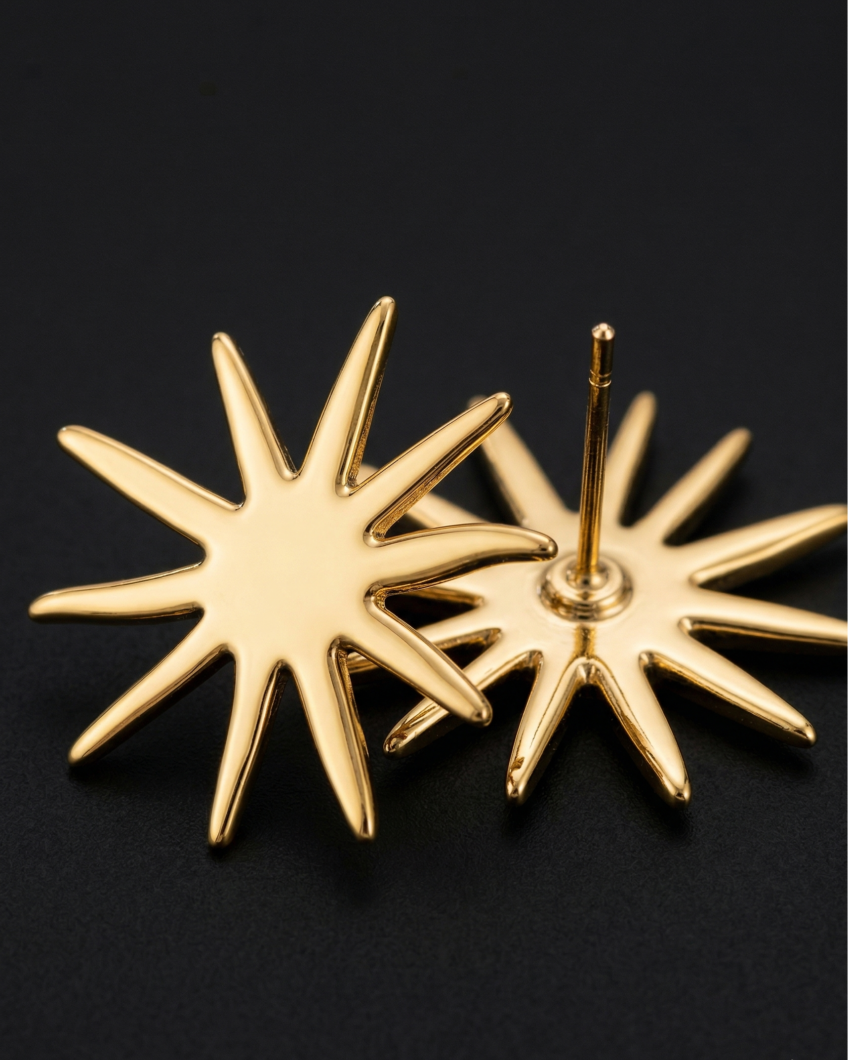 Gold star-shaped earrings on a black background