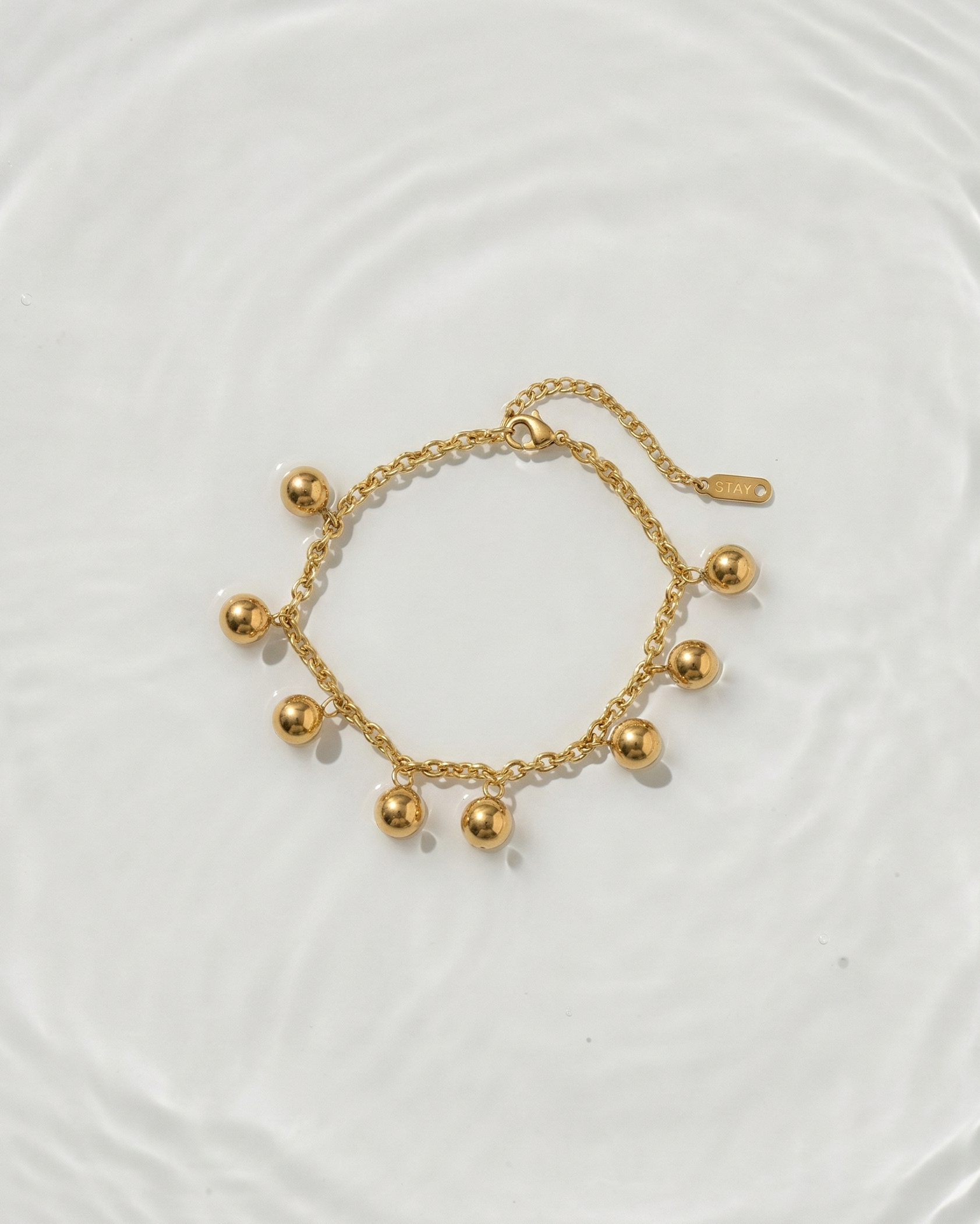 Gold bracelet with spherical charms on a light background