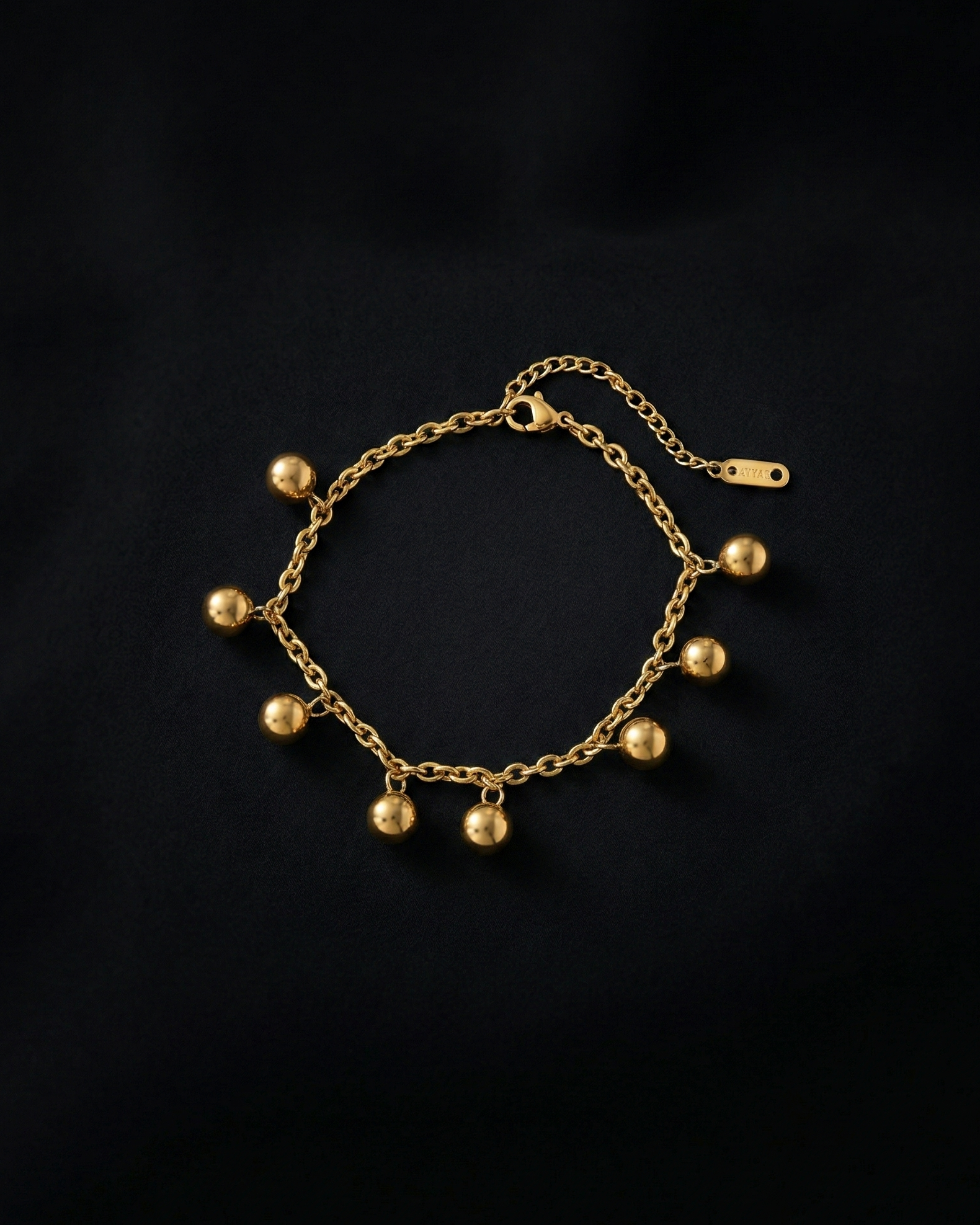 Gold bracelet with spherical charms on a black background