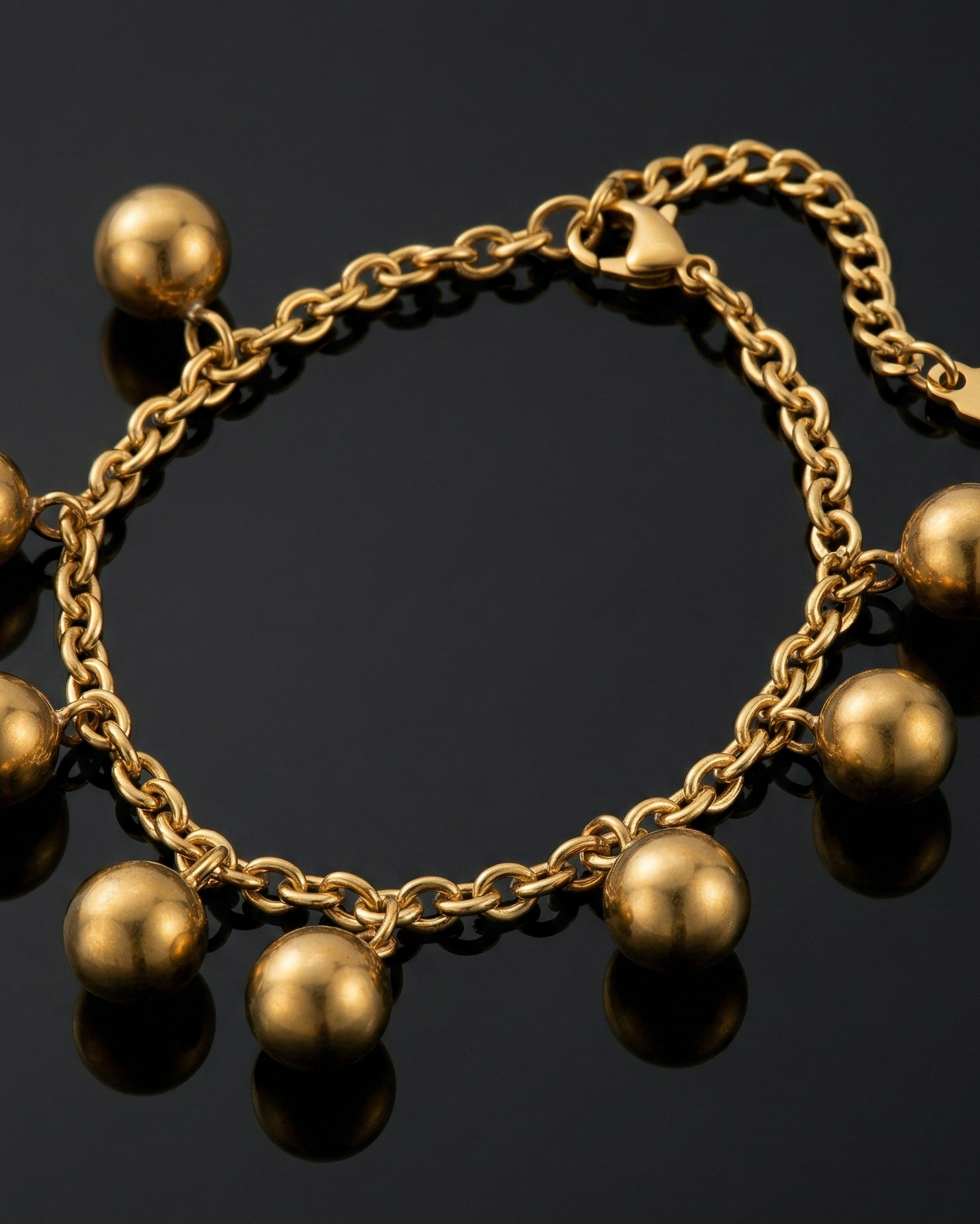 Gold bracelet with spherical beads on a black background