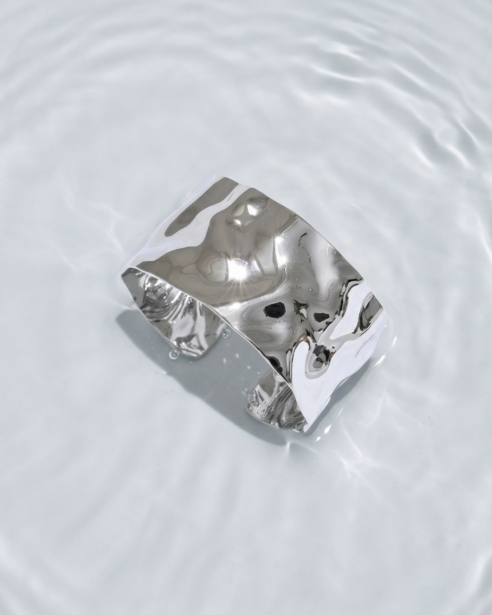 Silver ring with a textured design on a water surface