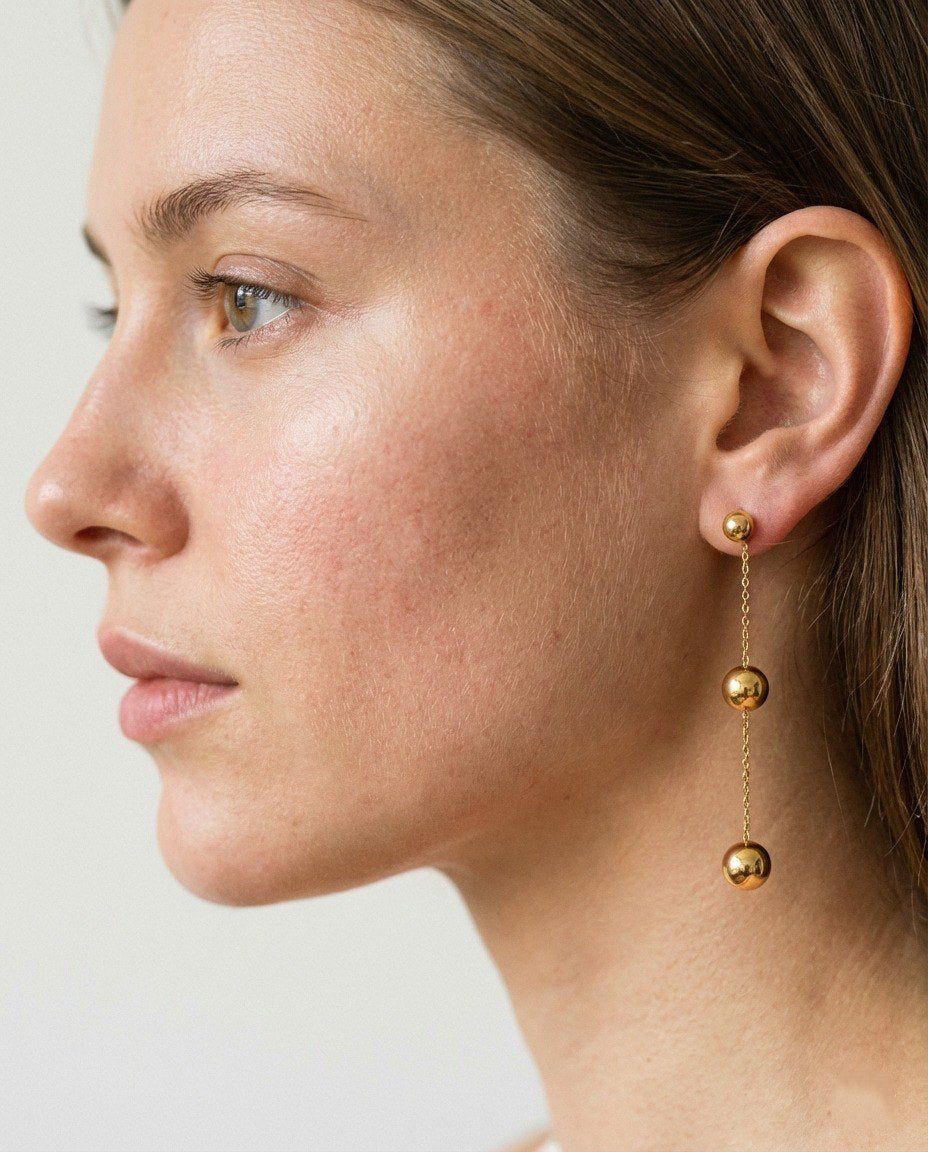 Close-up of a woman wearing gold earrings with a plain background