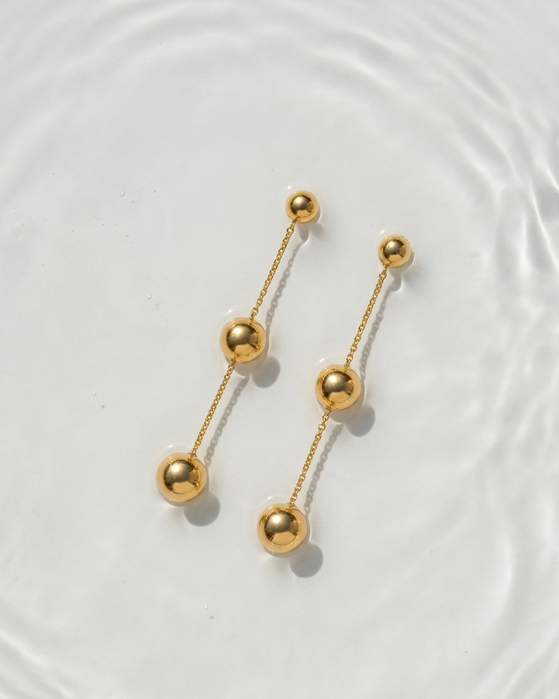 Gold earrings with spherical beads on a light background