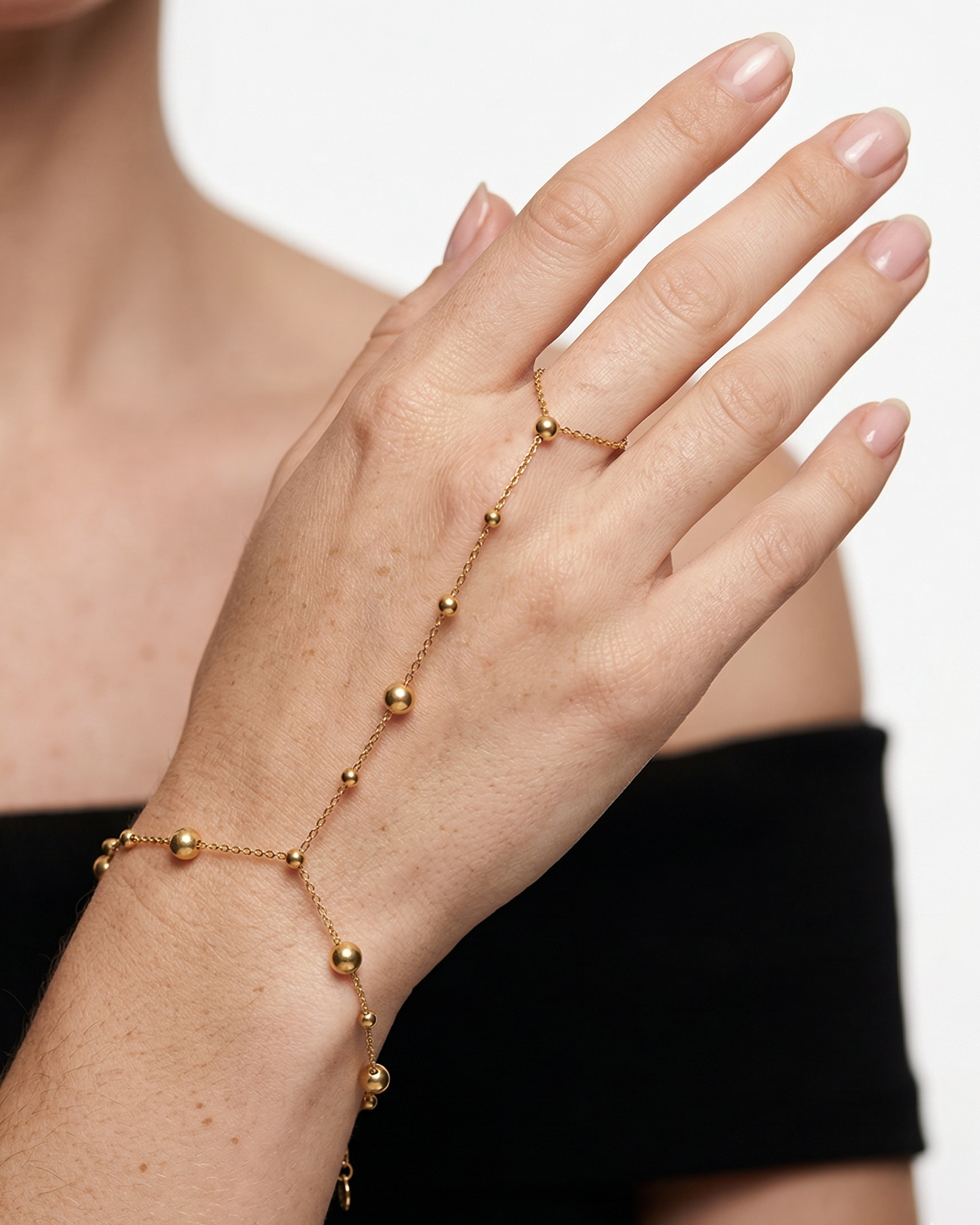 Gold beaded bracelet on a person's wrist with a plain background