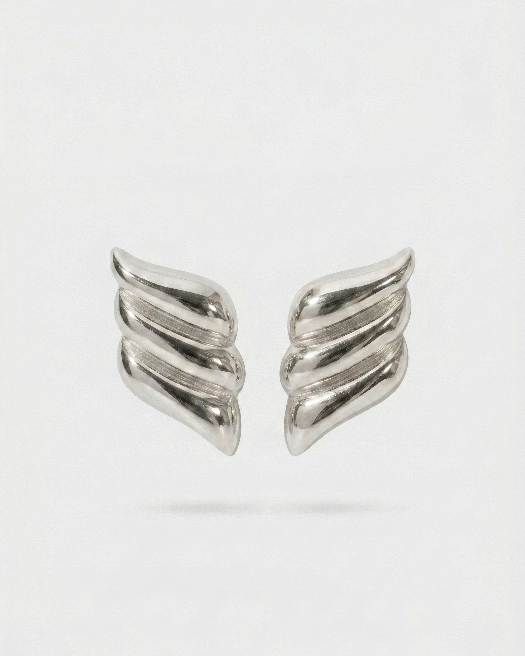 Pair of silver wing-shaped earrings on a light gray background