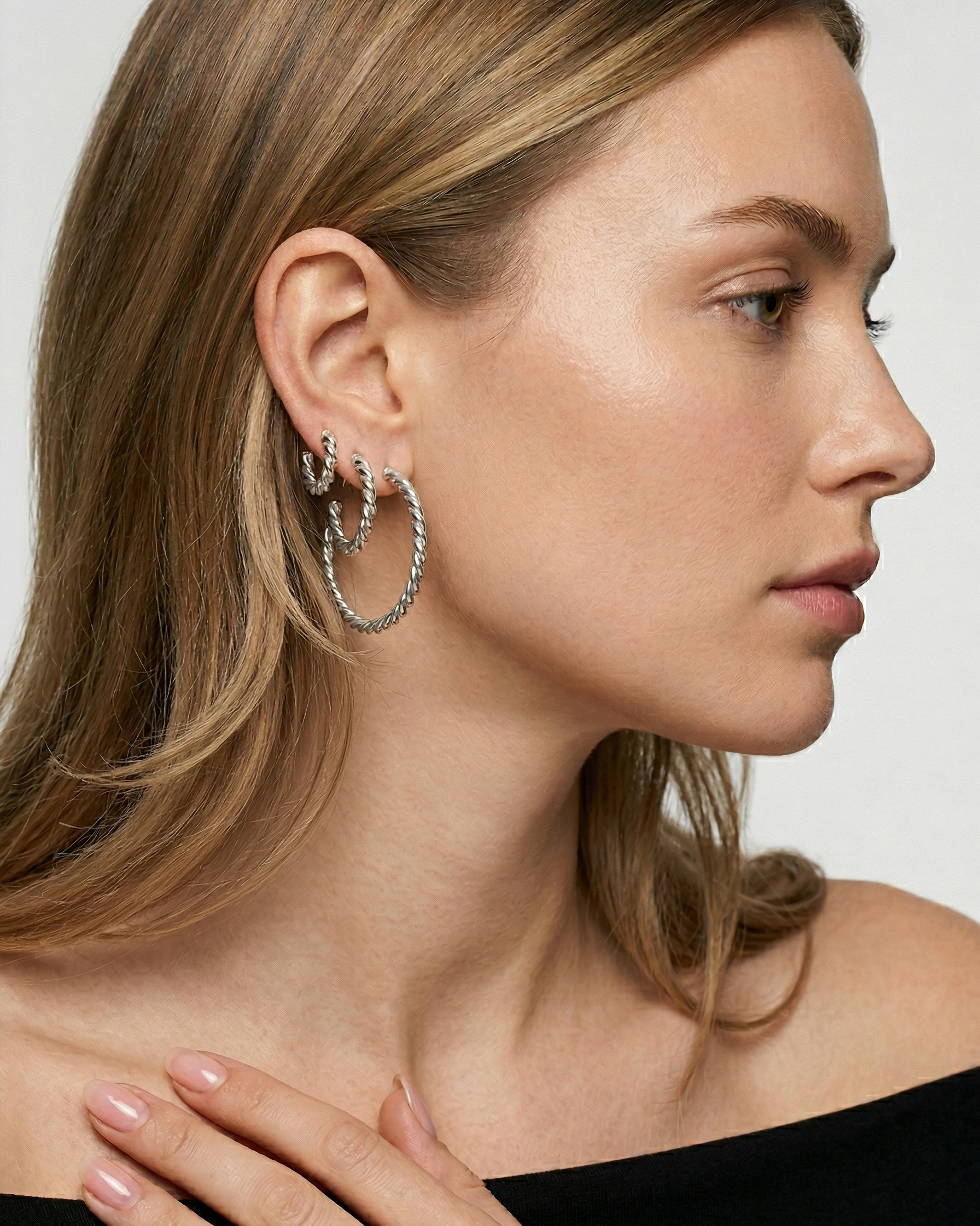 Woman wearing hoop earrings with a neutral background