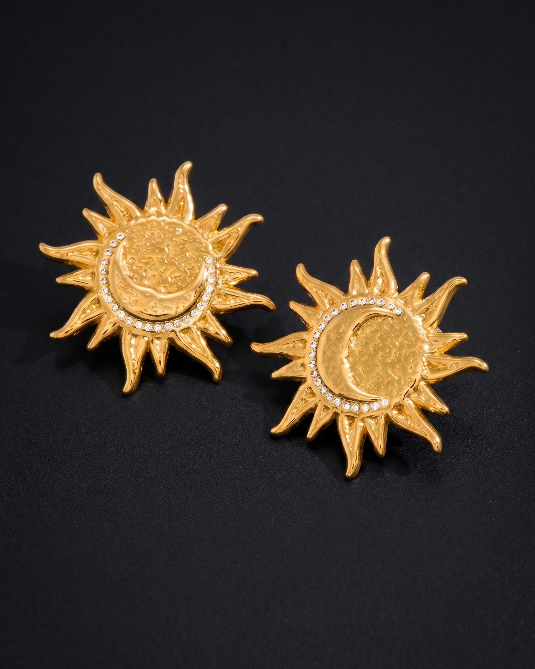 Gold sun and moon earrings on a black background