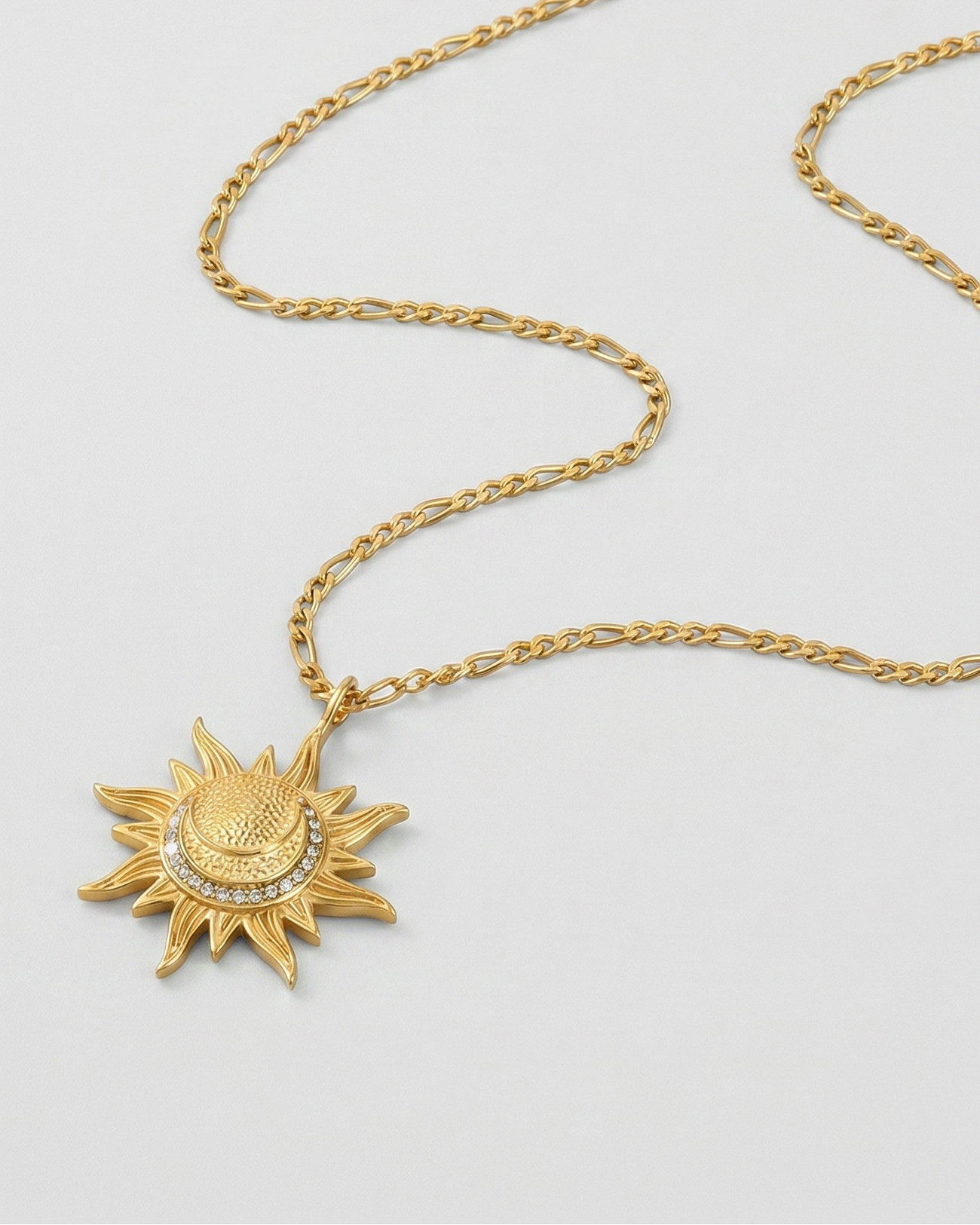 Gold necklace with sun pendant on a light gray background