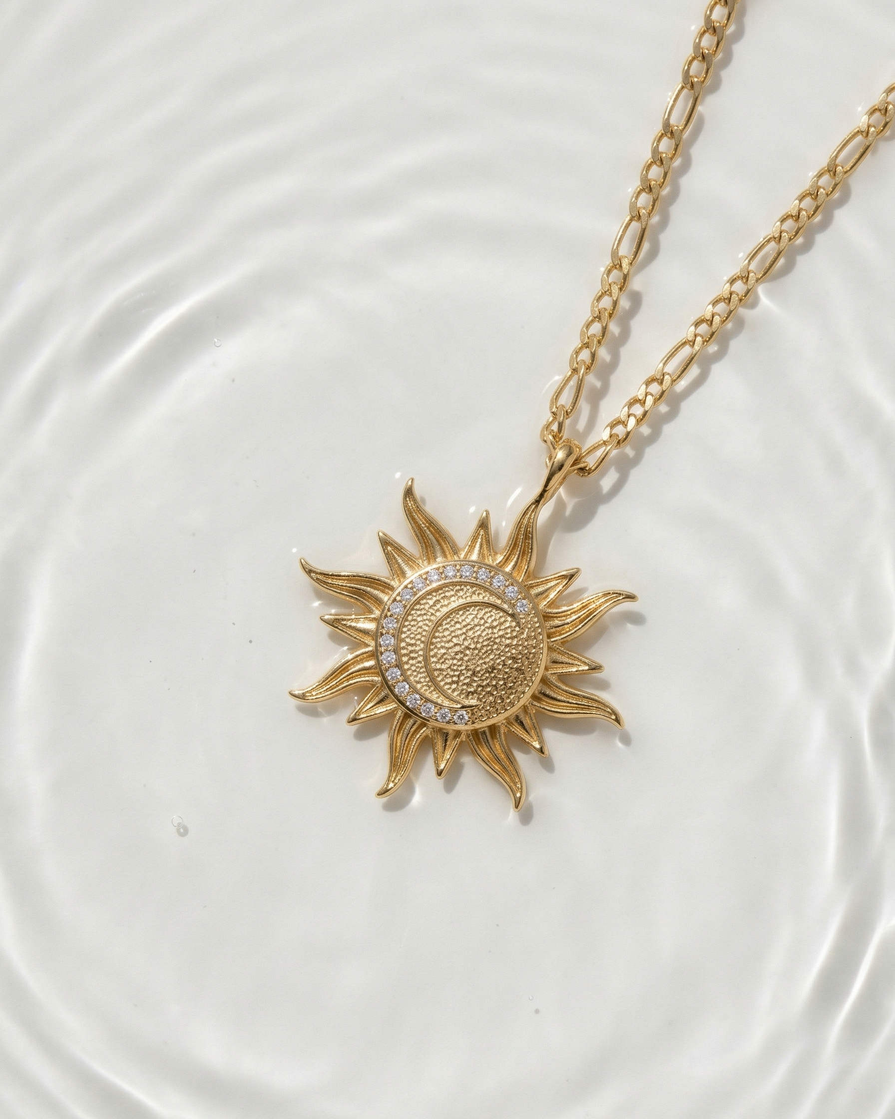Gold necklace with sun and moon pendant on a white background