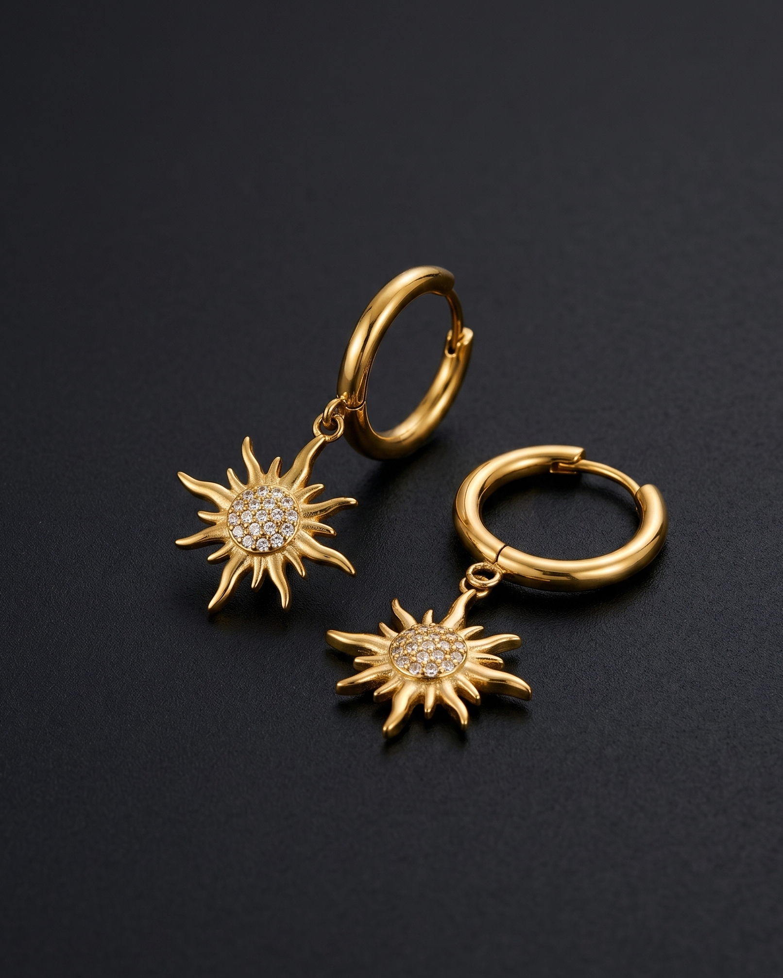 Gold hoop earrings with sunflower designs on a black background
