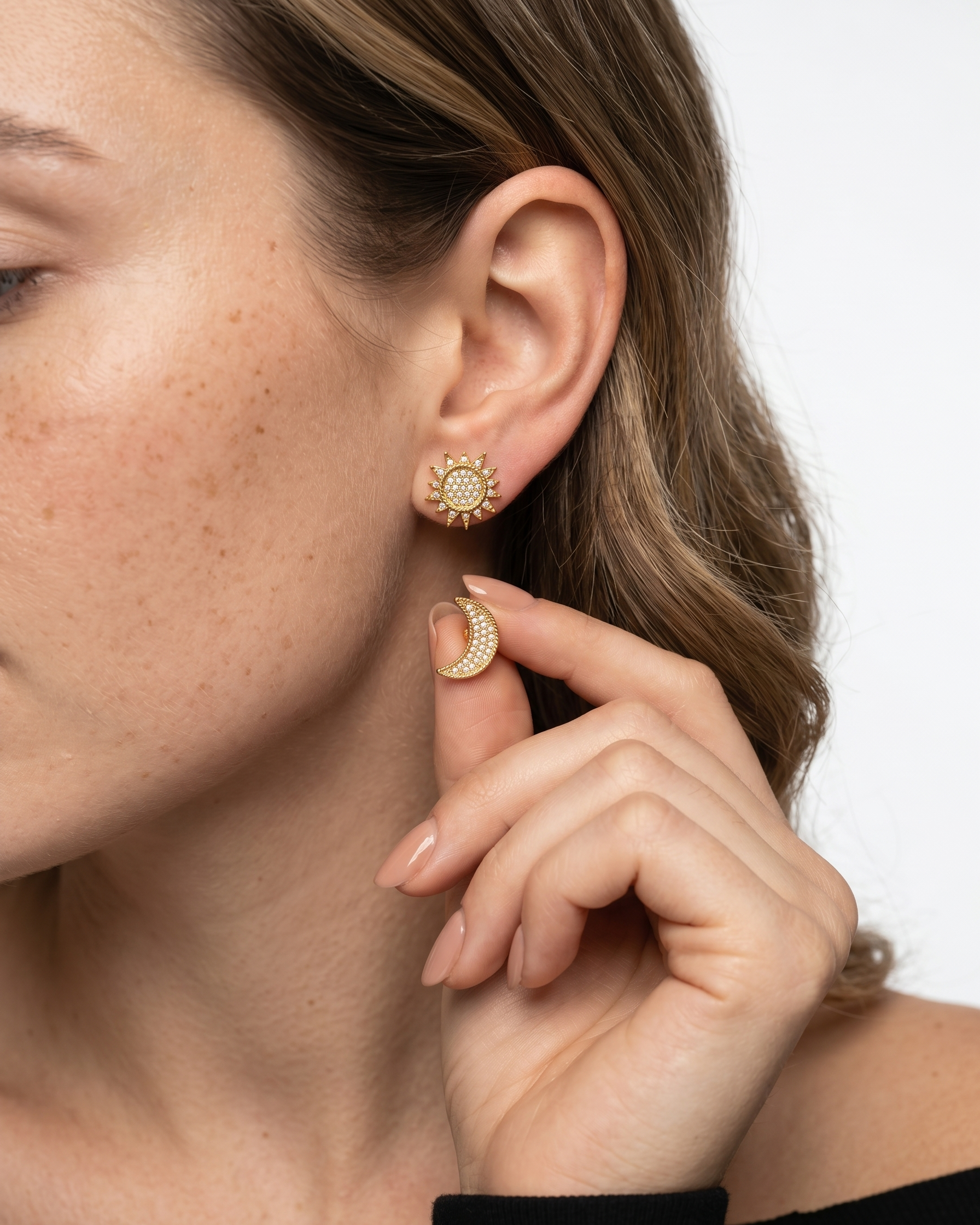 Close-up of a woman wearing gold earrings with a plain background