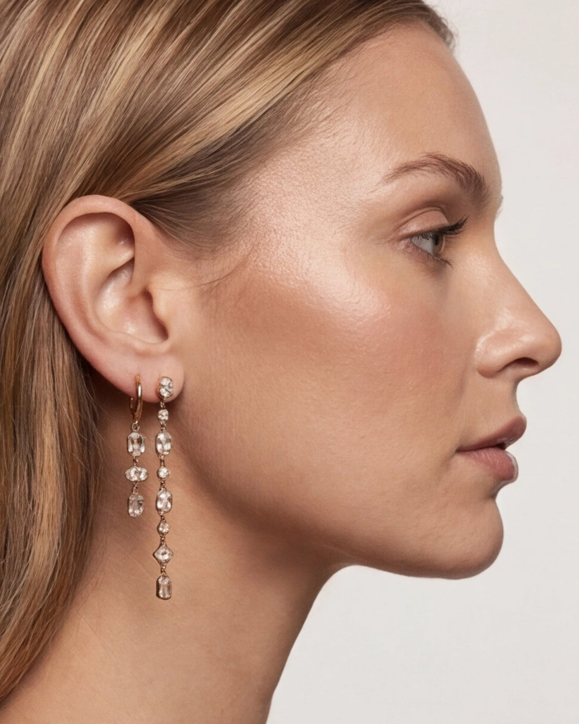 Close-up of a woman wearing a dangling earring with a plain background