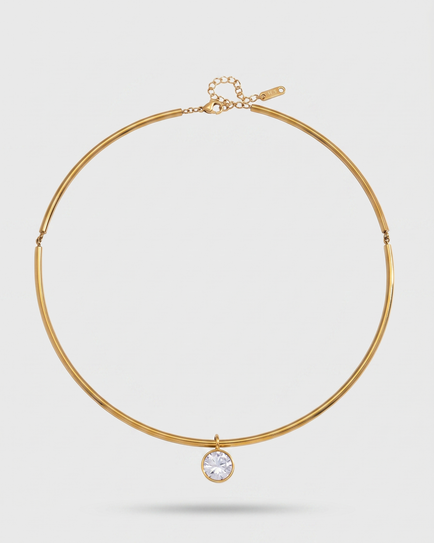 Gold necklace with a diamond pendant on a light gray background