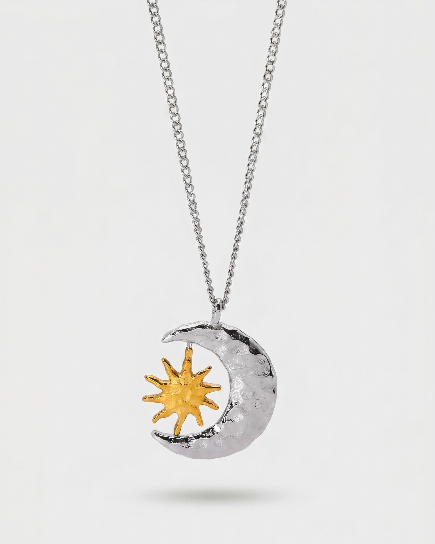 Silver necklace with a sun and moon pendant on a white background