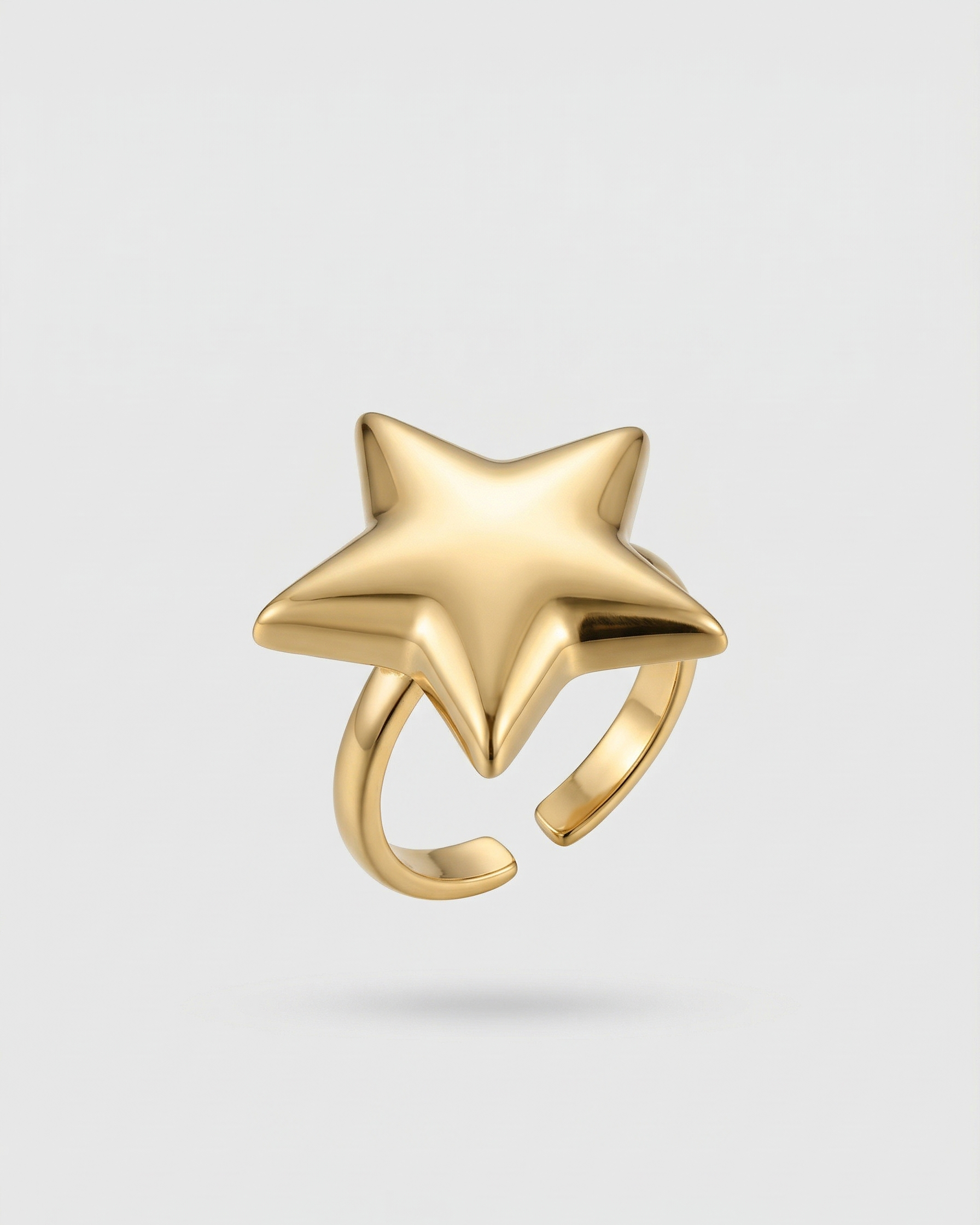 Gold star-shaped ring on a light gray background