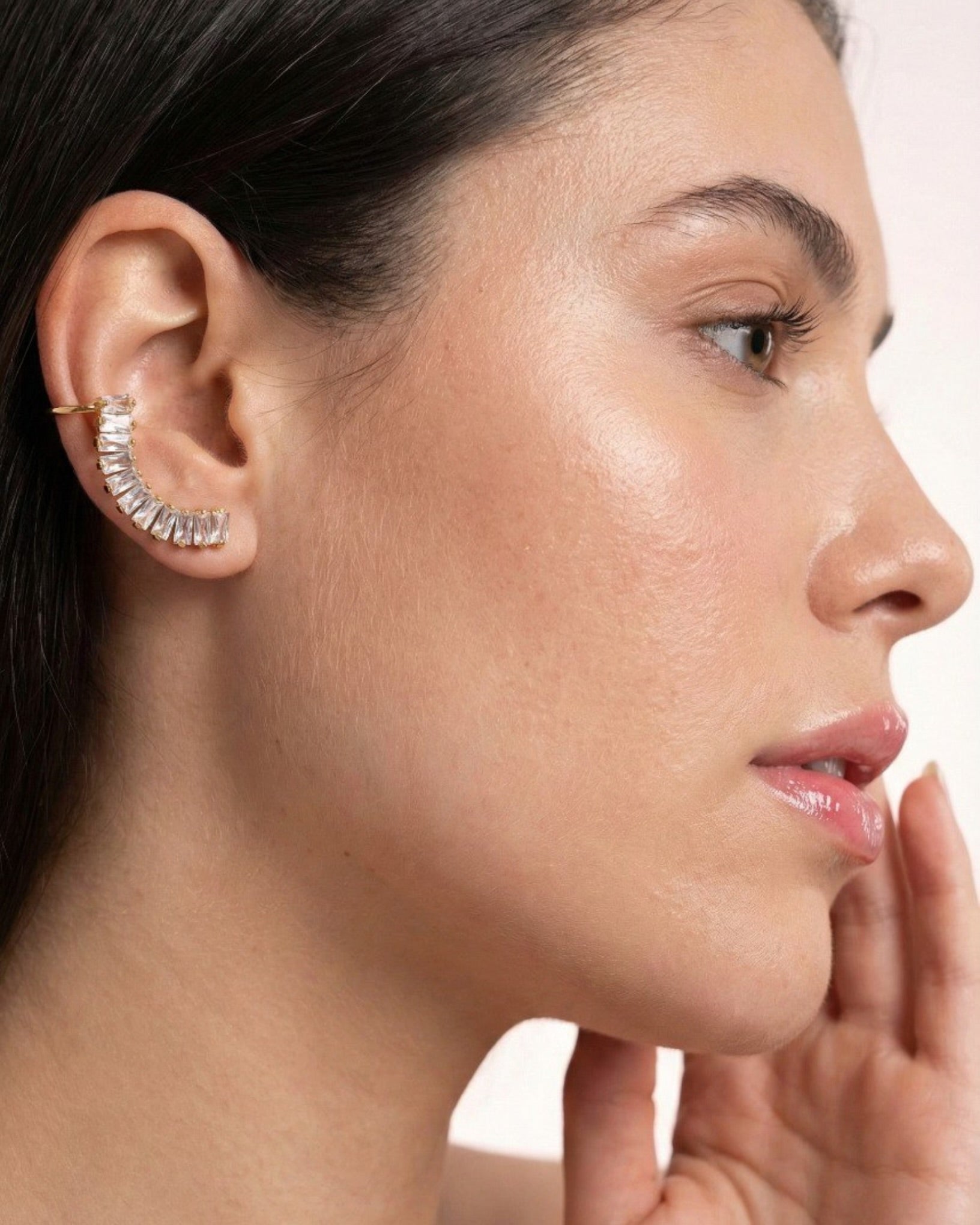 Close-up of a woman's ear wearing a diamond earring with a blurred background