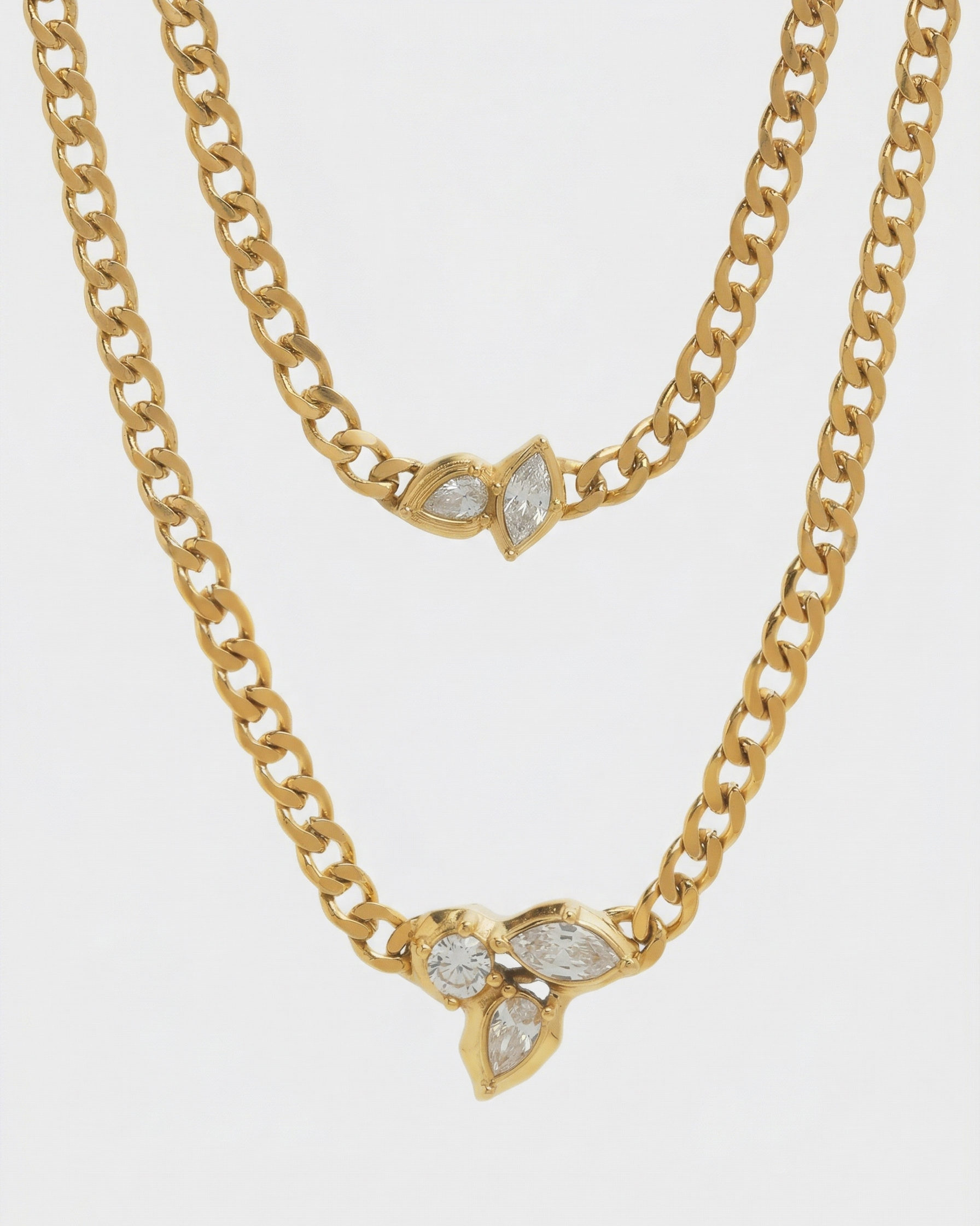 Two gold chain necklaces with leaf-shaped pendants on a white background