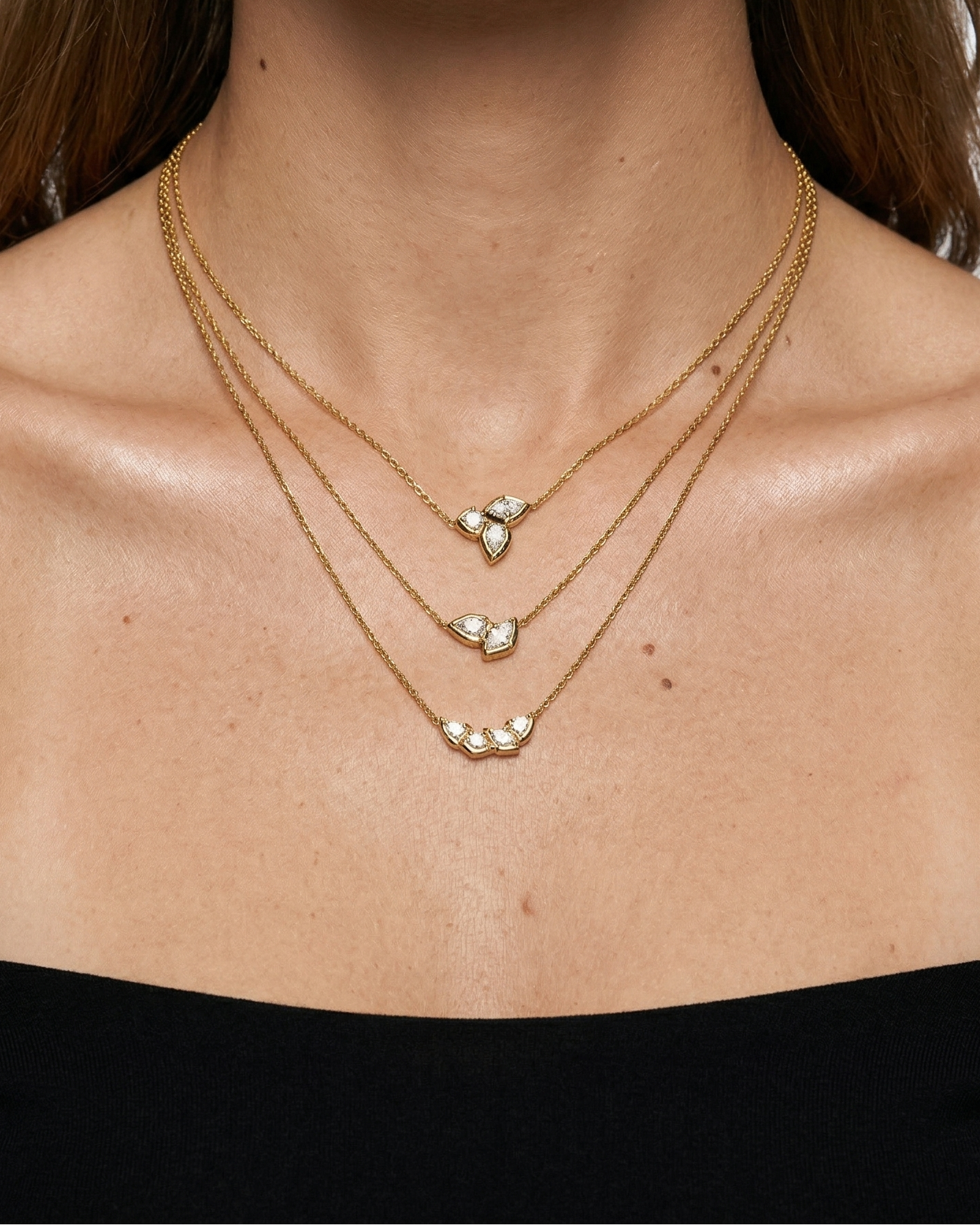 Close-up of a person wearing two gold necklaces with heart pendants on a white background