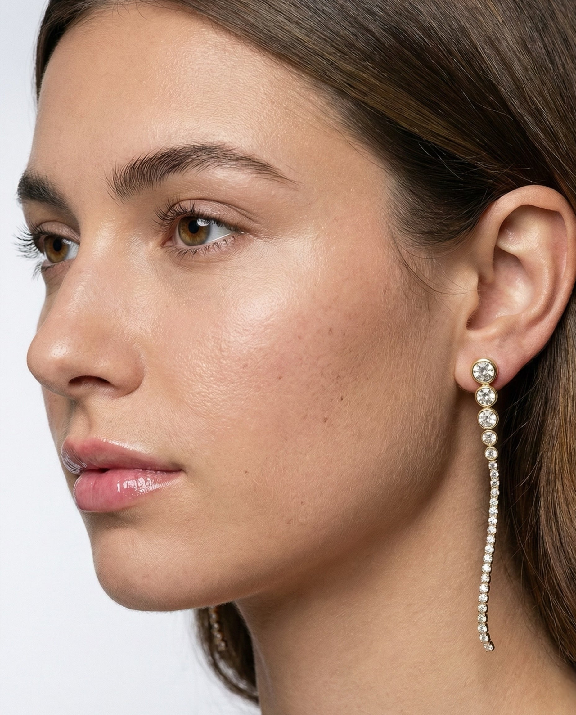 Close-up of a woman wearing a dangling earring with a white background