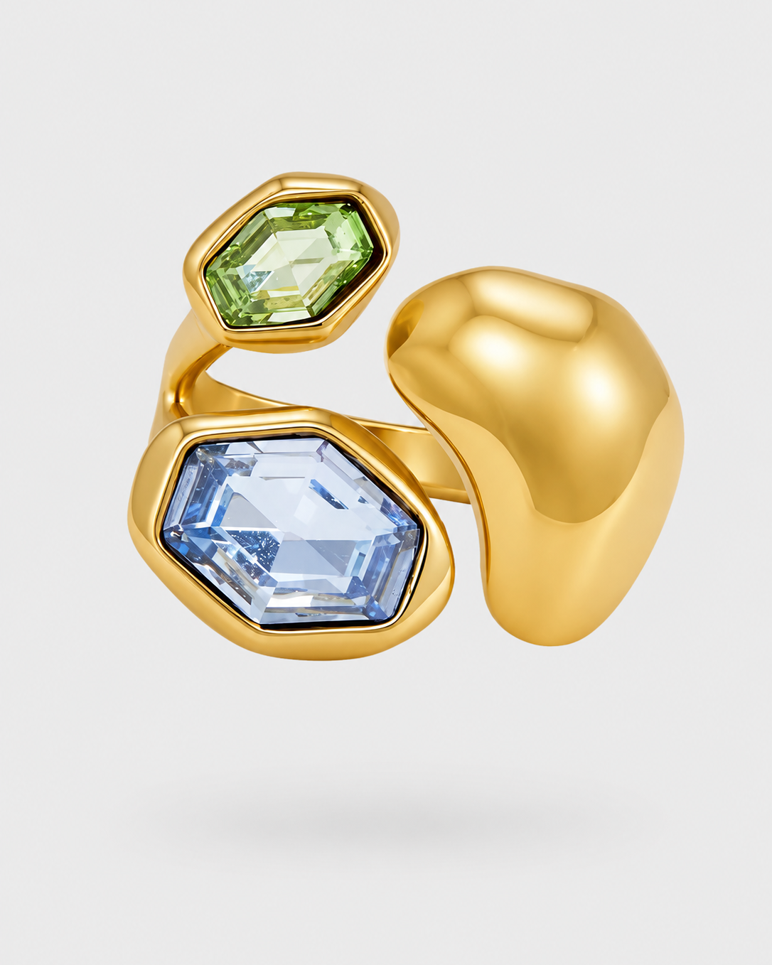 A gold ring featuring two hexagonal gemstones, one light green and one light blue, set against a clean light gray background.