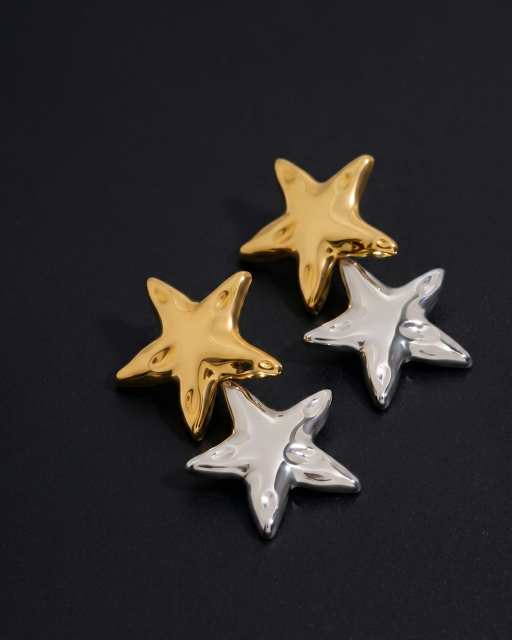 Four star-shaped buttons, two gold and two silver, on a black background.
