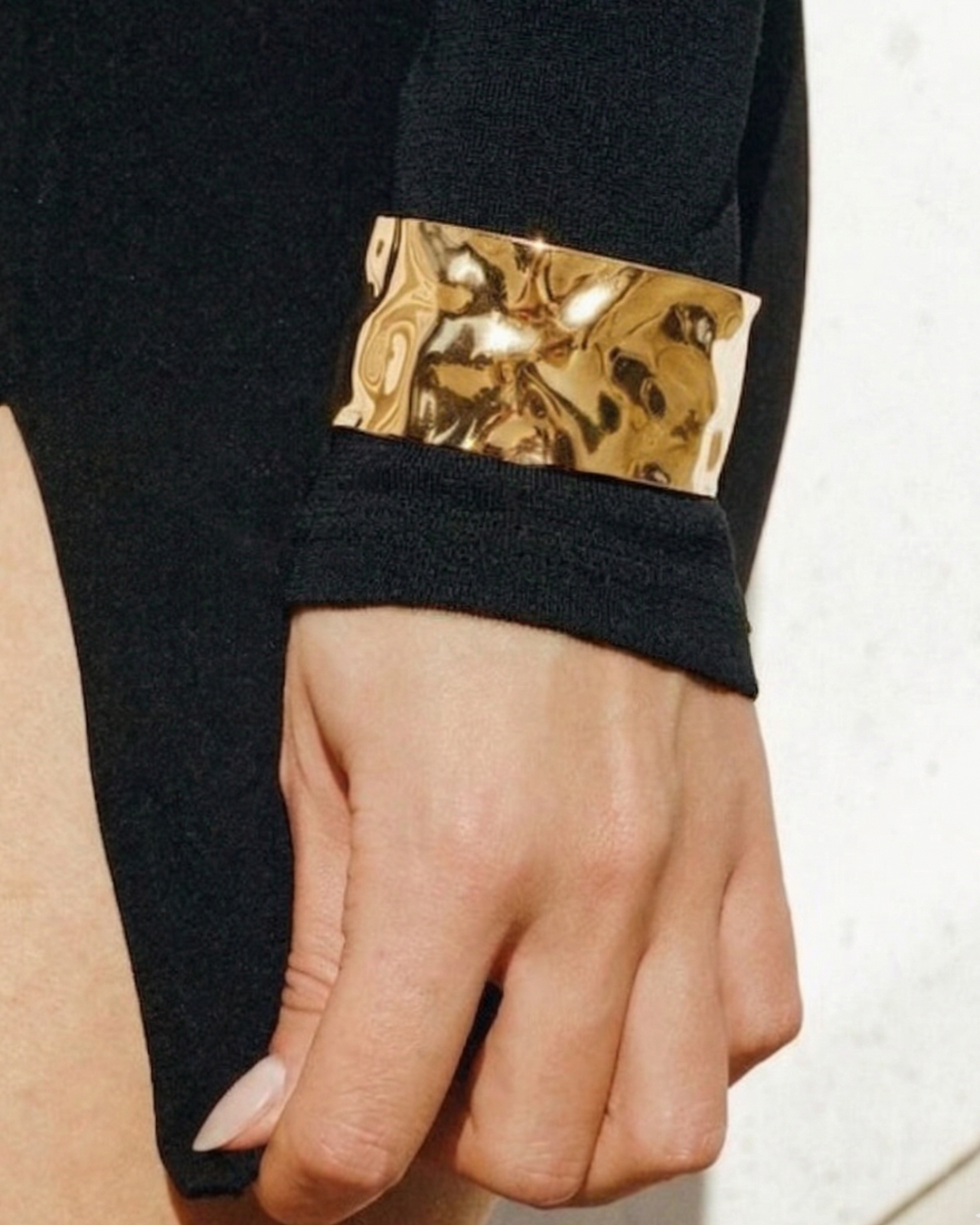 Black sleeve with gold metallic cuff on a white background