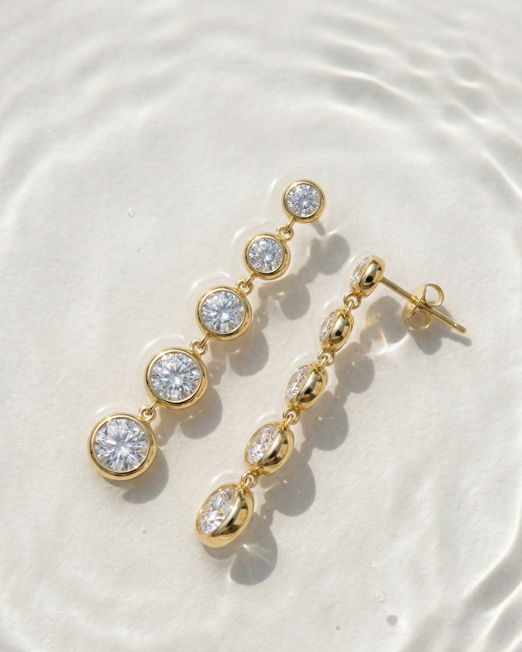 Gold earrings with clear gemstones on a white surface