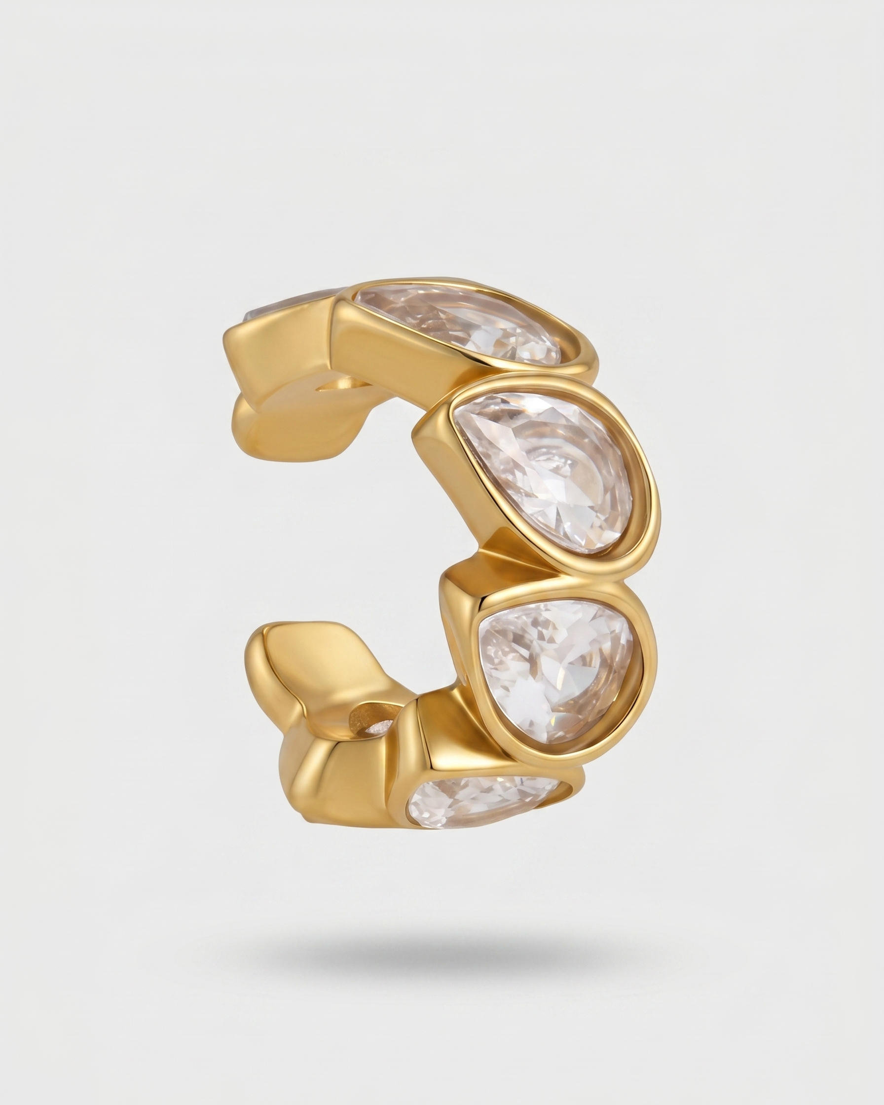 Gold ring with clear gemstones on a light gray background
