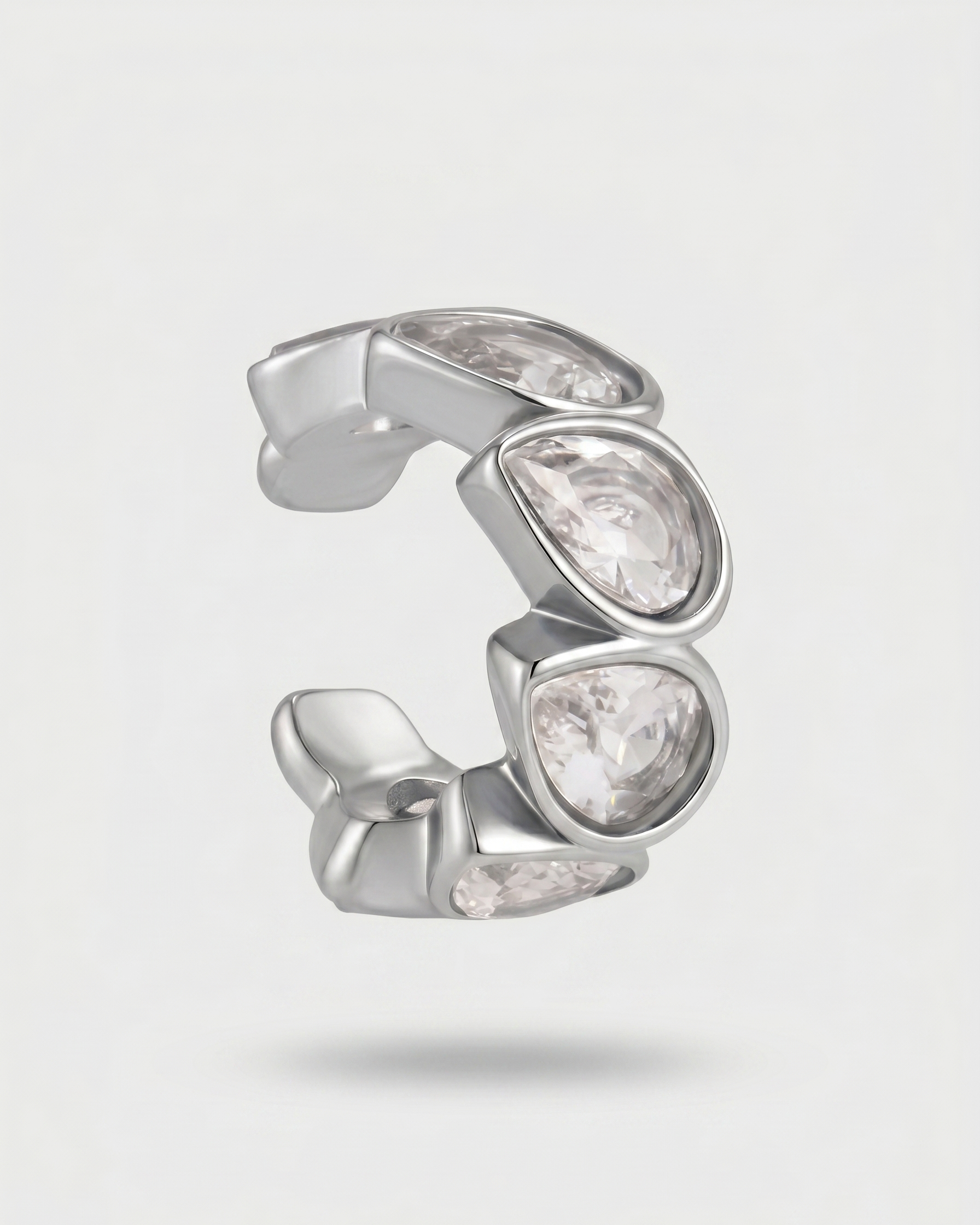Silver earring with clear gemstones on a light gray background