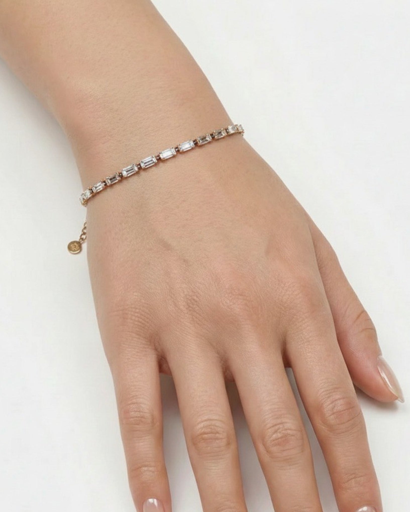 Hand wearing a delicate bracelet on a white background