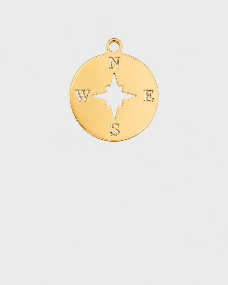 A gold circular compass pendant charm with N, S, E, and W lettering and a central rose design, shown on a light gray background.