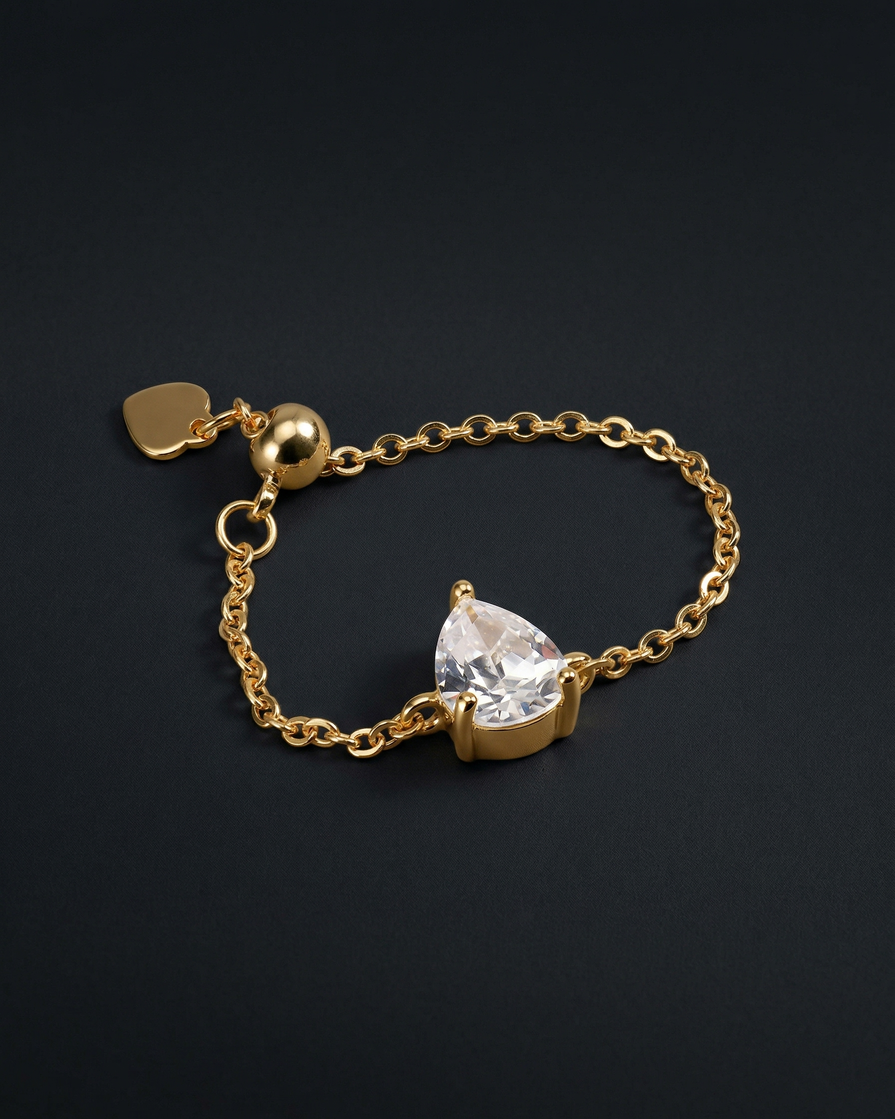 Gold bracelet with a teardrop-shaped diamond on a black background