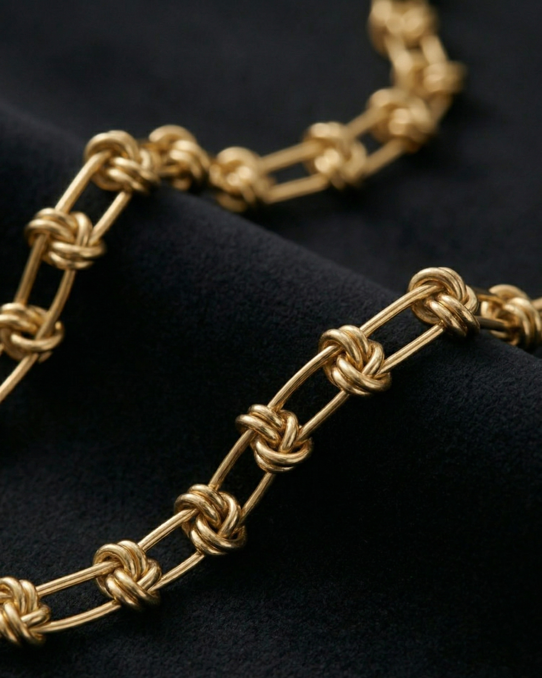 Gold chain necklace on a dark fabric background