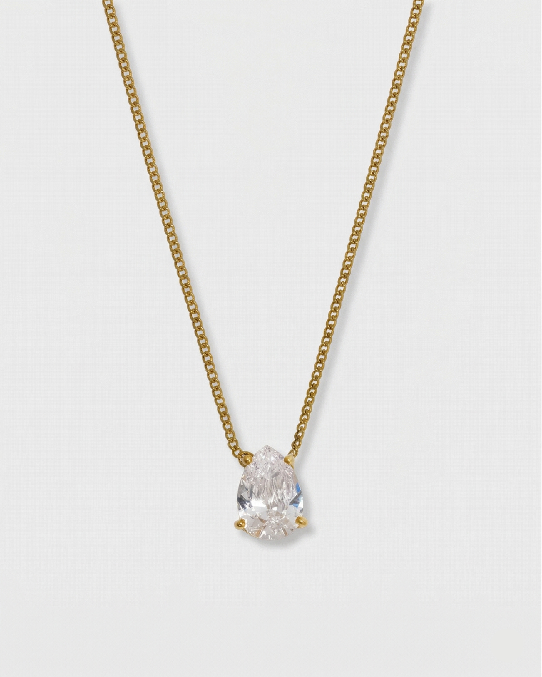 Gold necklace with a pear-shaped diamond pendant on a light gray background