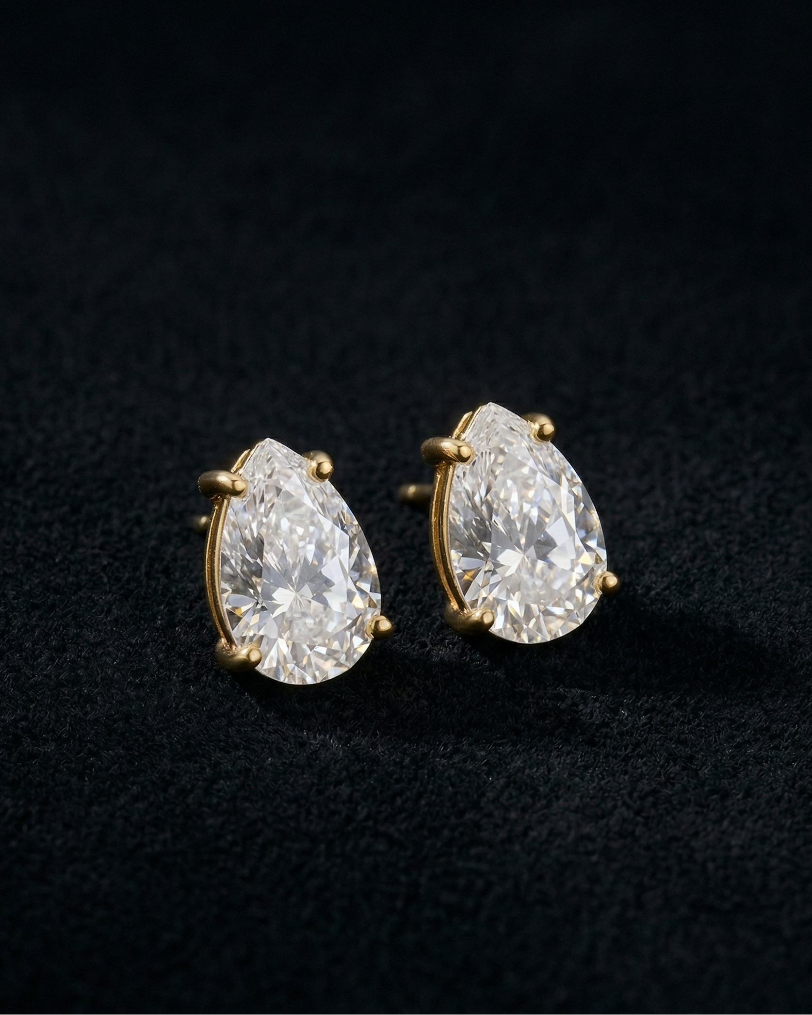 Pair of pear-shaped diamond earrings on a black background