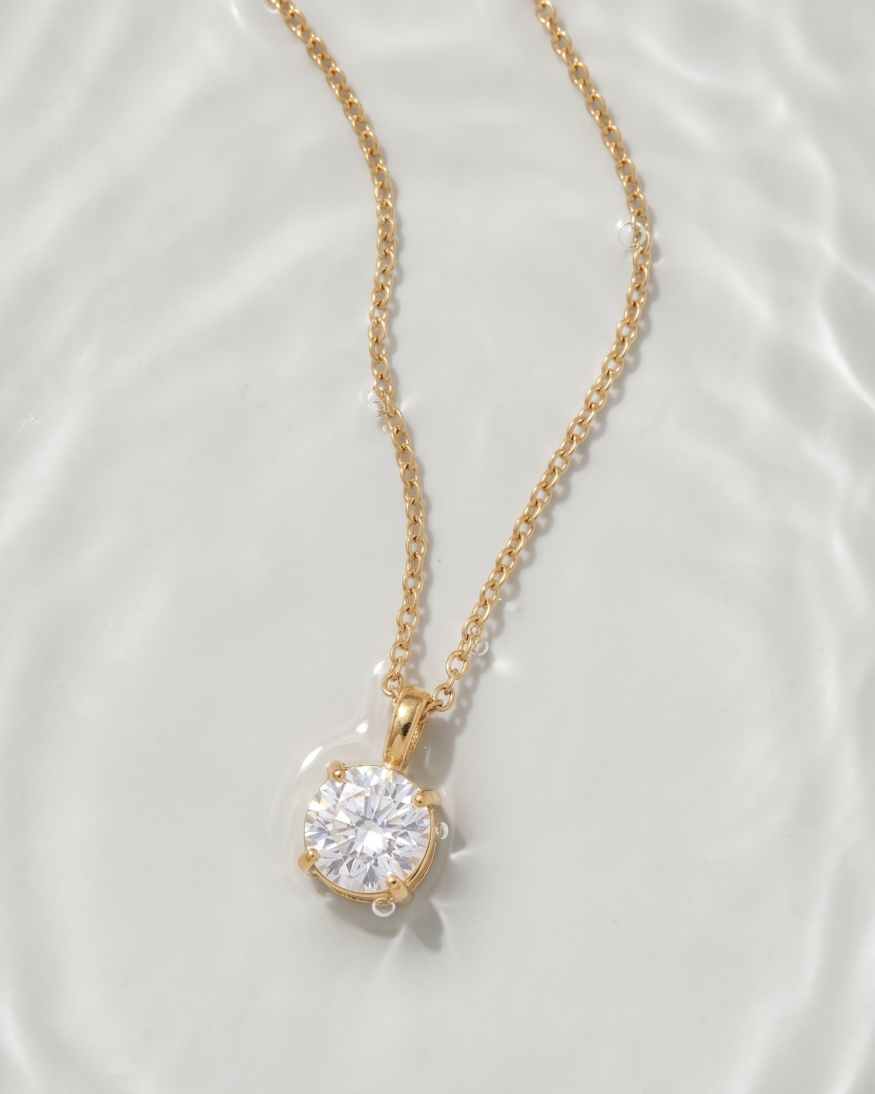 Gold necklace with a diamond pendant on a white background