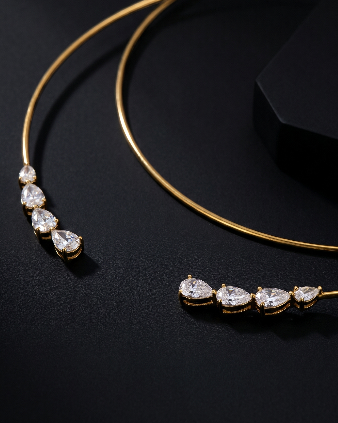 Gold necklace with teardrop-shaped gemstones on a black background