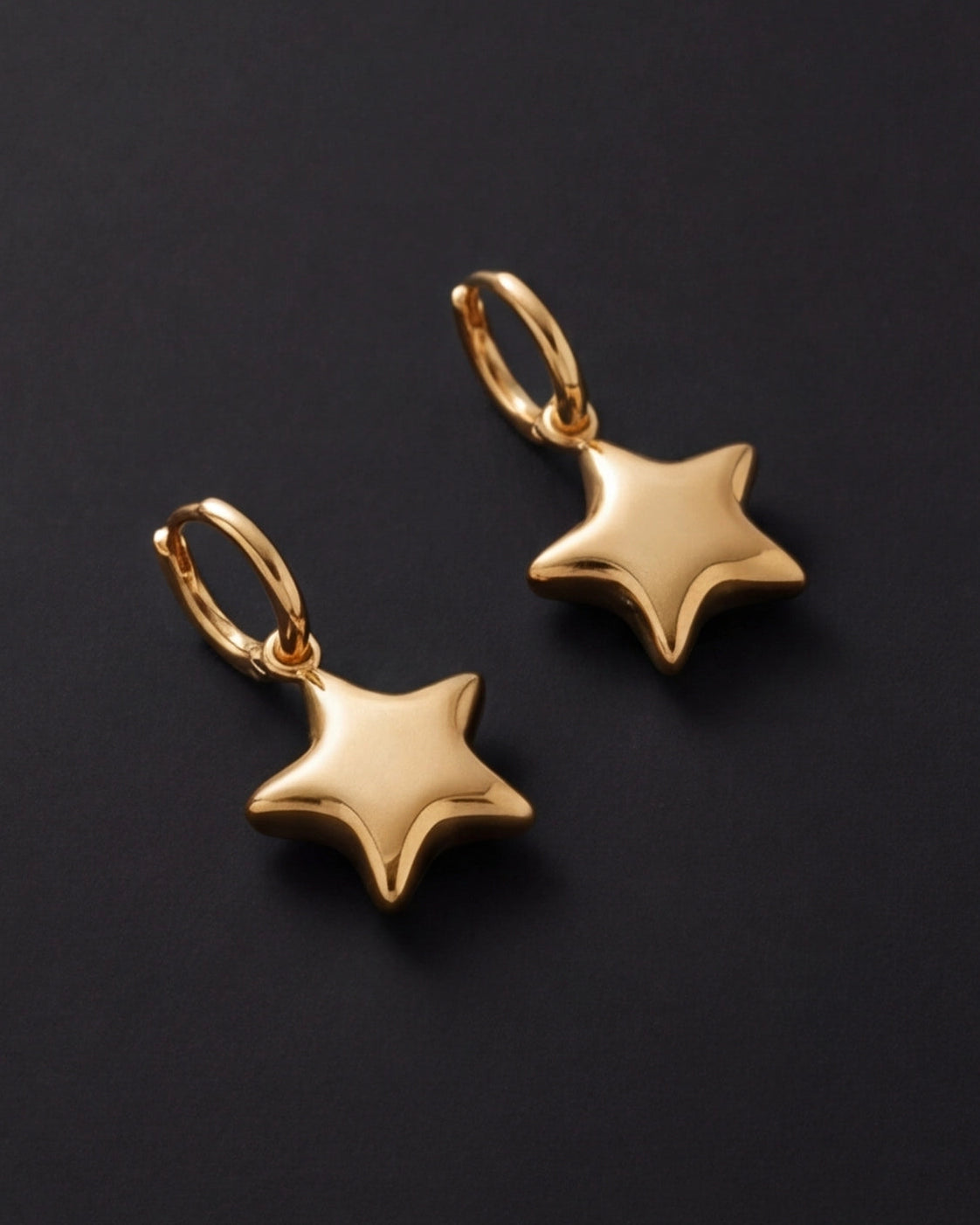 Gold star-shaped earrings on a black background