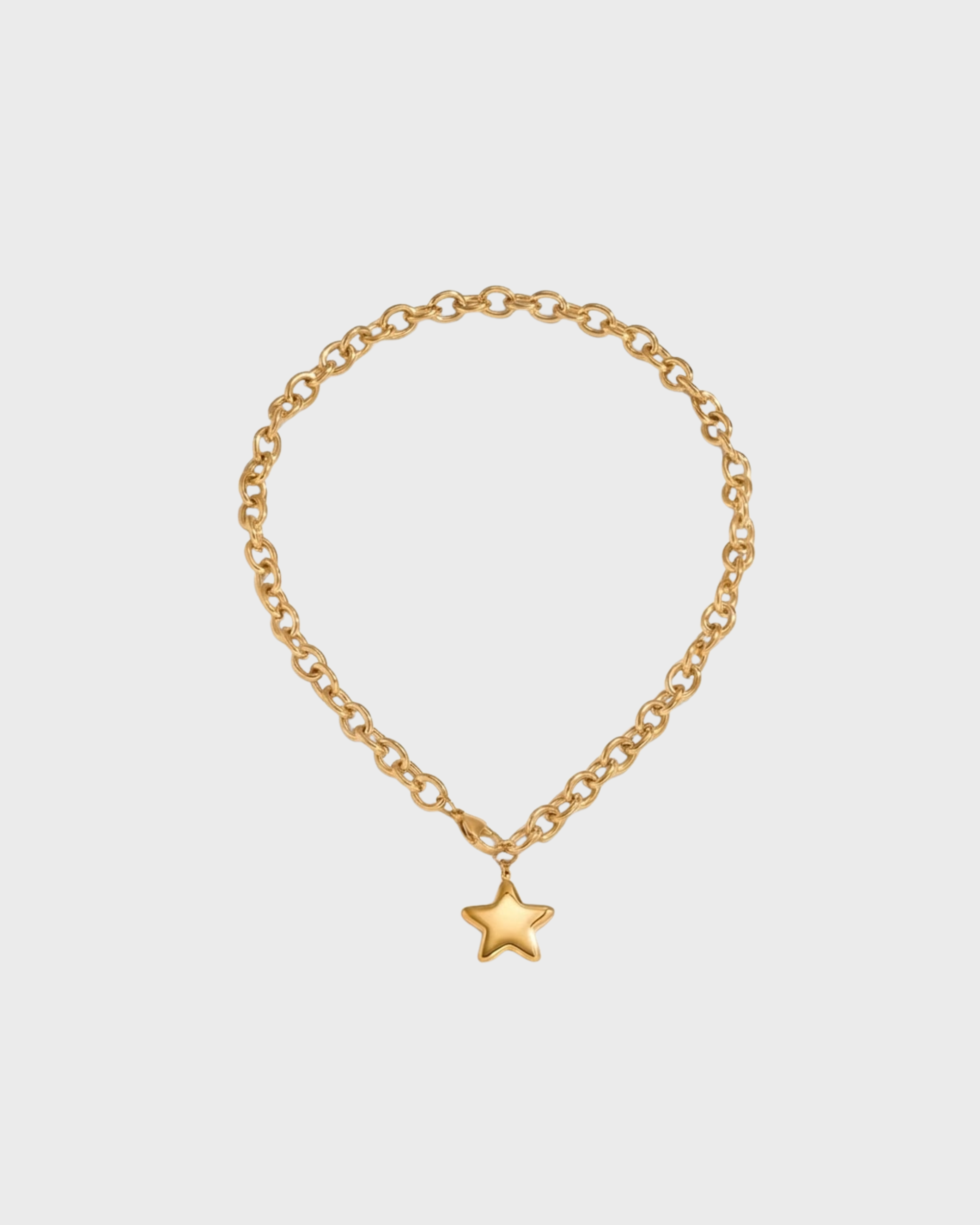 Gold chain bracelet with a star charm on a light gray background