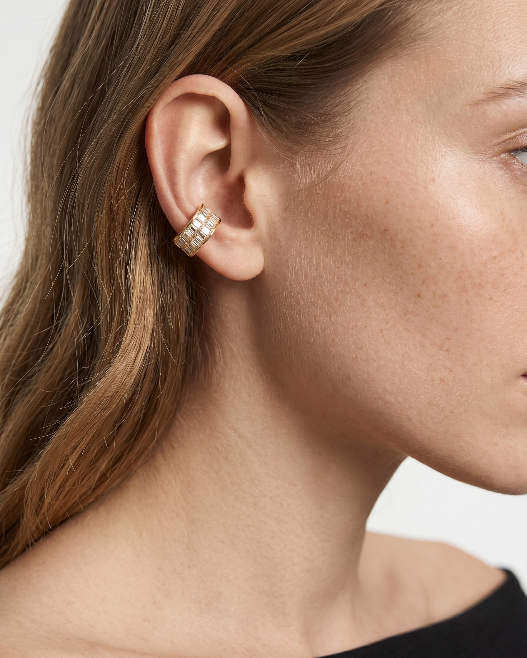 Close-up of a woman wearing a gold hoop earring with a white background